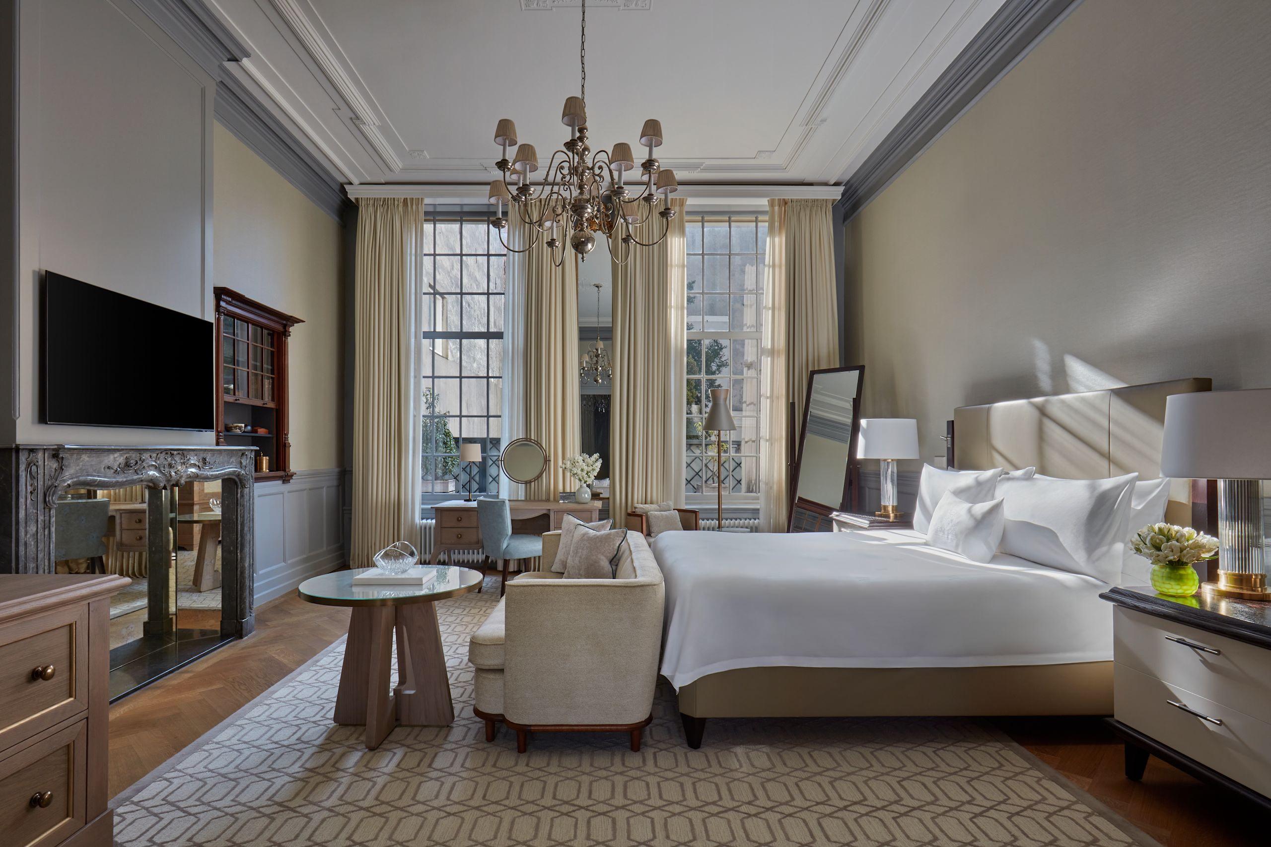Waldorf Astoria Amsterdam: a bedroom with cream paneled walls, high ceilings with cornice details, and windows overlaid with ornate frames