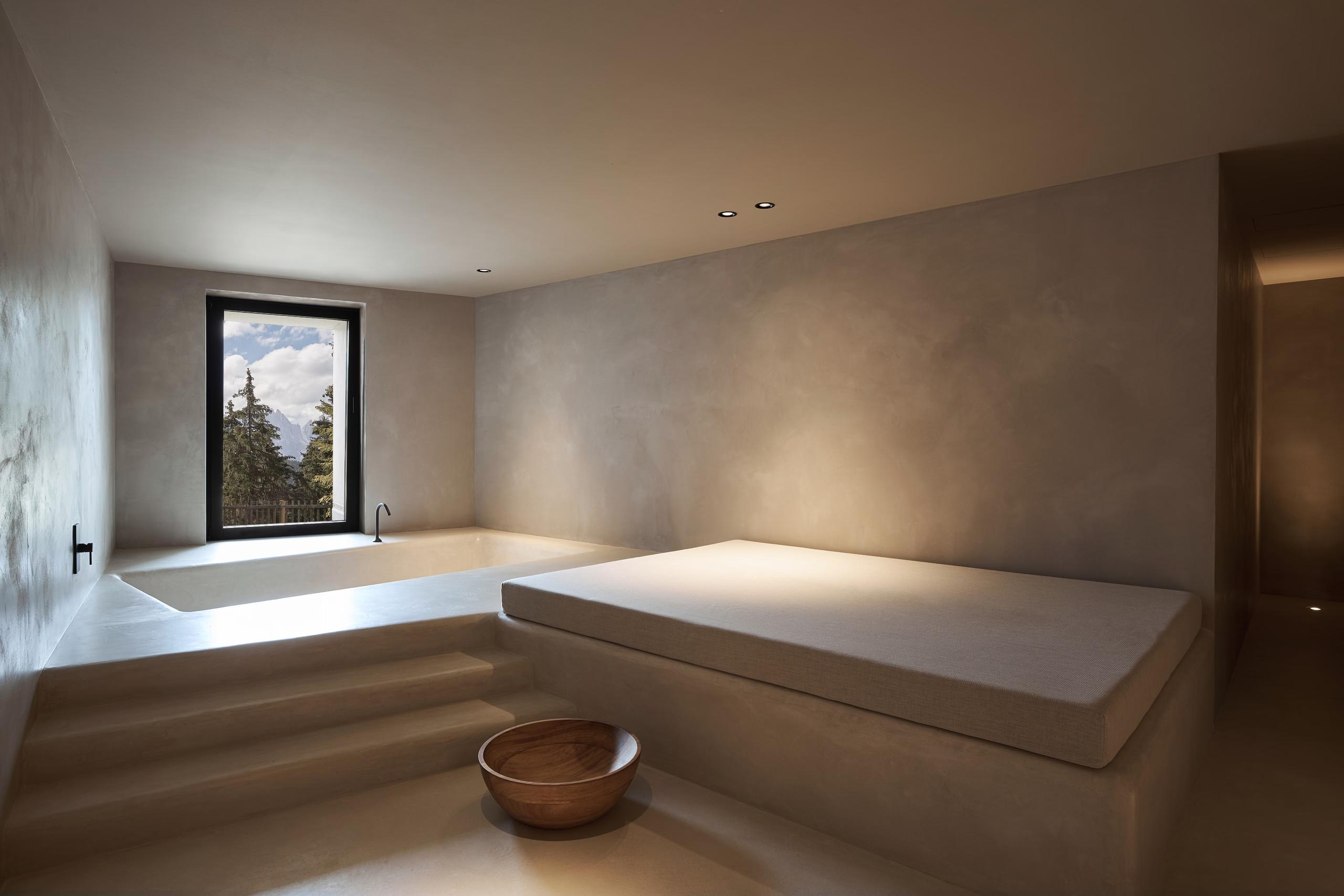Forestis: a spa treatment room with light wood and stone surfaces, minimal furnishings, and soft natural light