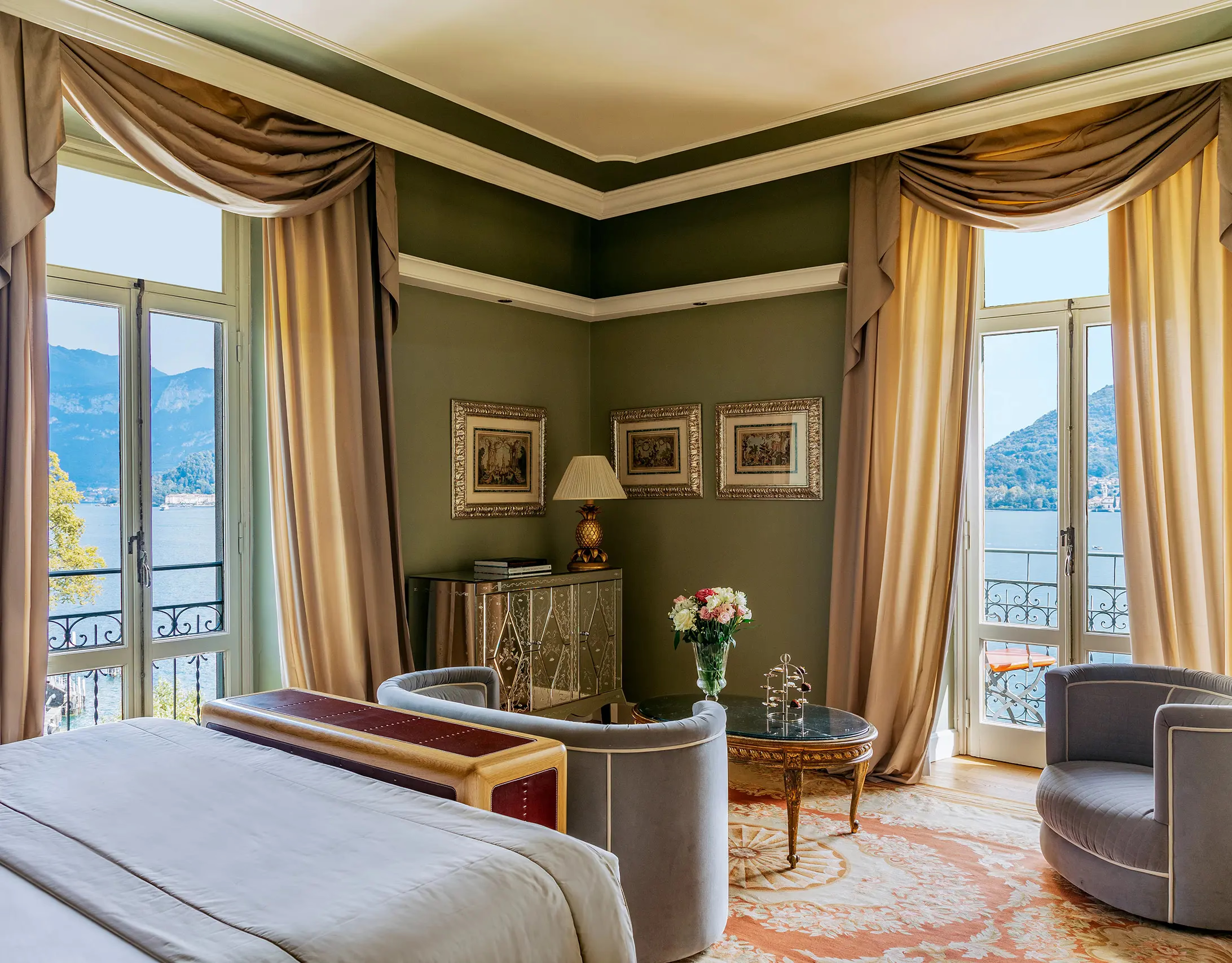 Bedroom with sage-green walls, draped windows, and balcony with distant lake views
