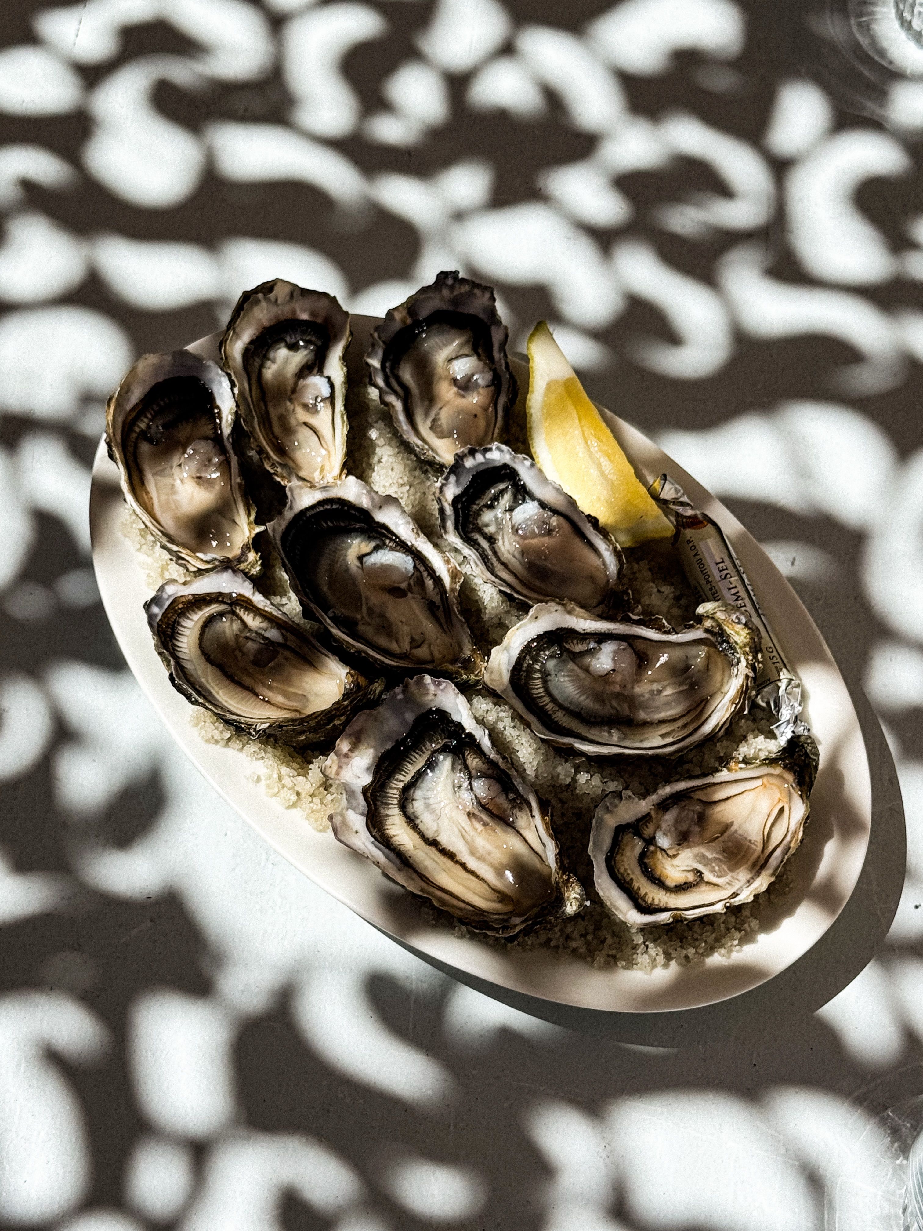 A platter of oysters with a wedge of lemon in dappled shade at Poissonnerie Kennedy