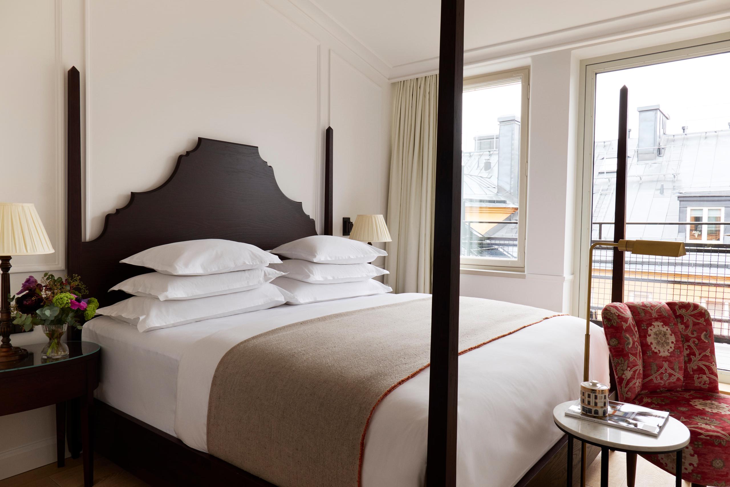 Villa Dagmar: guest bedroom with dark canopy bed, white linens, and windows with city views