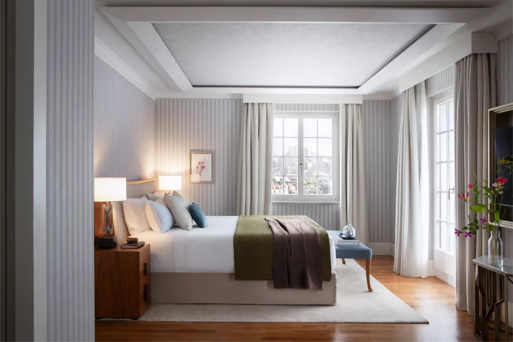 Light-filled bedroom suite with coffered ceiling, bed canopy, and lake-view windows