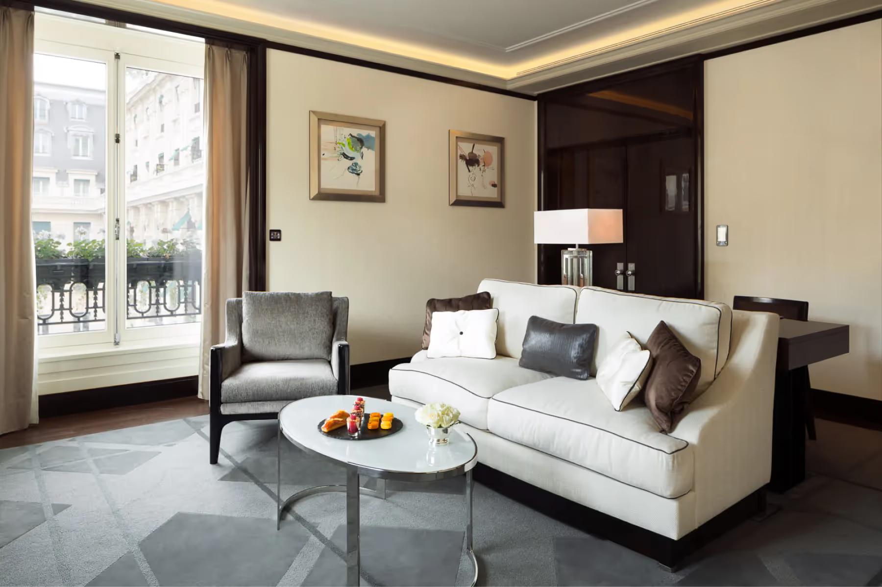 The Peninsula: suite living room with cream sofa, wood accents, louvered closet doors, and tall windows
