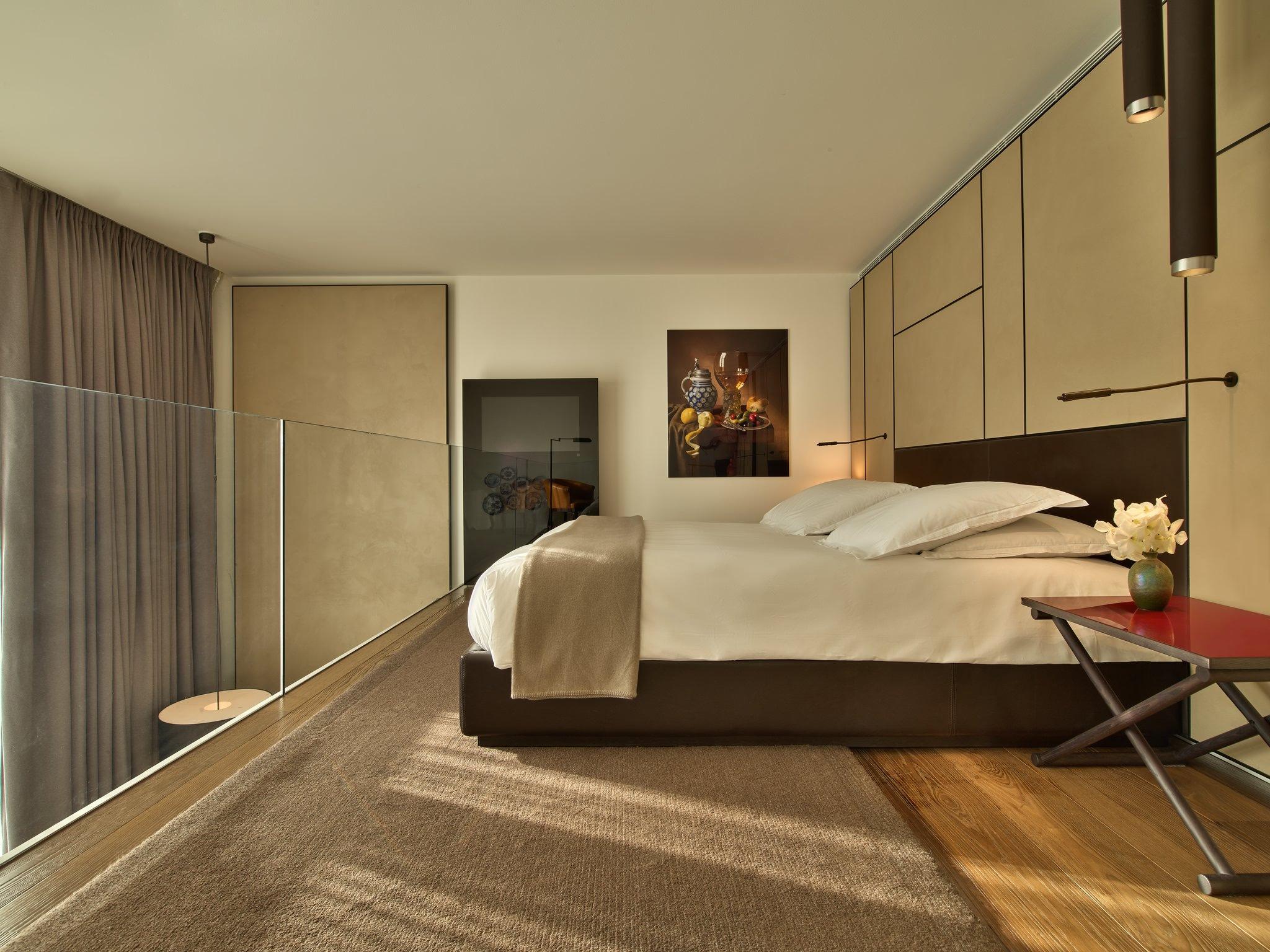 Mandarin Oriental Conservatorium, Amsterdam: minimalist bedroom with a charcoal bed frame, cream linens, and floor-to-ceiling windows with curtains