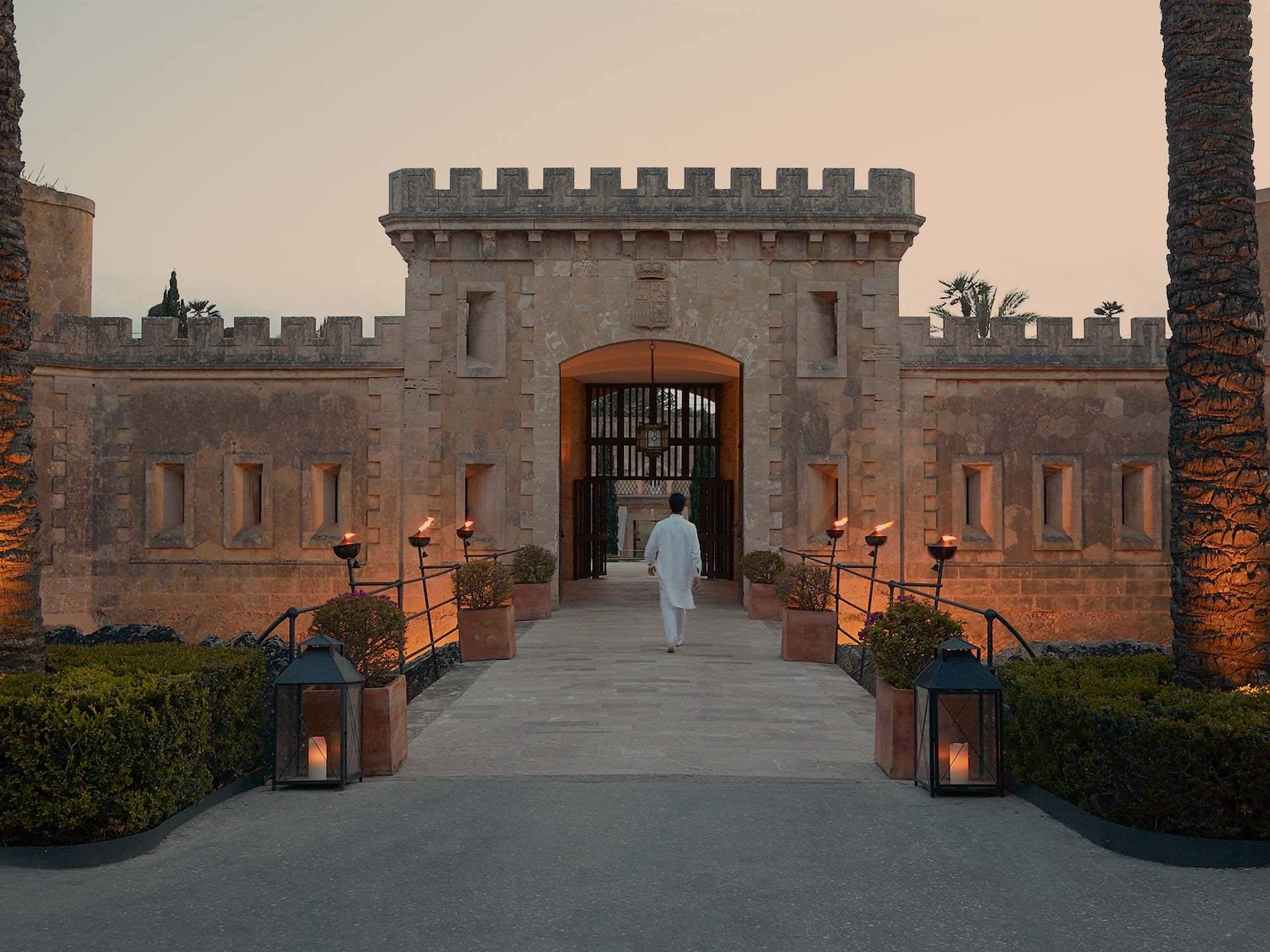 Cap Rocat: a crenellated fortress gate entrance at sunset, framed by stone archways and lanterns