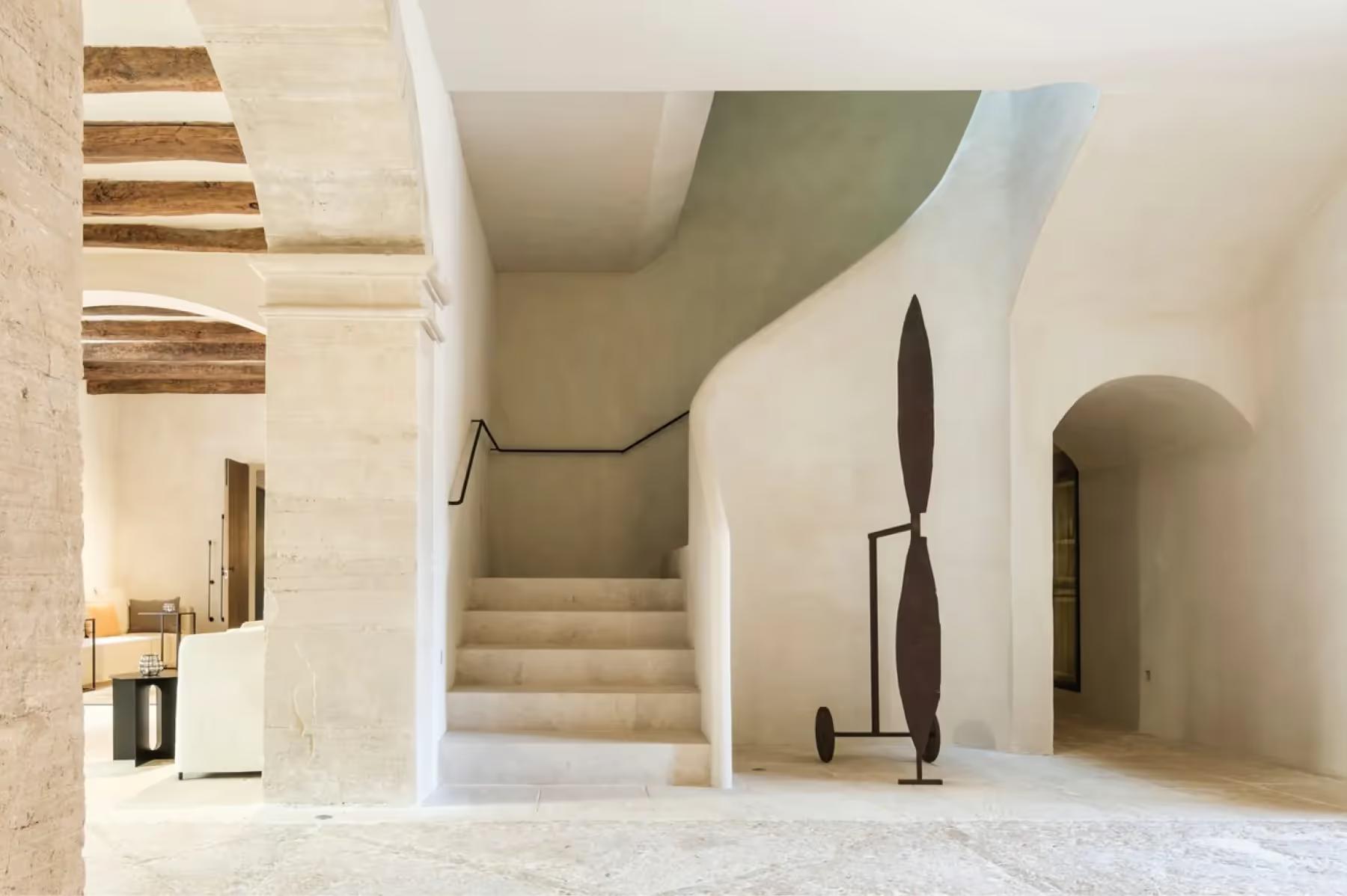 Can Ferrereta: minimalist hallway with stone archway and modern sculptural black decor