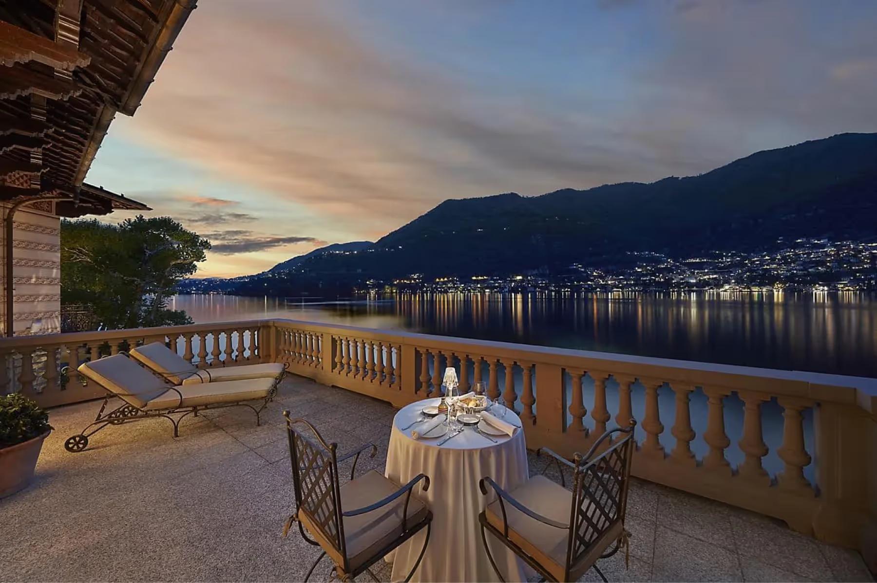 Mandarin Oriental, Lake Como: waterfront terrace at sunset with white furniture and distant mountains reflected in still water
