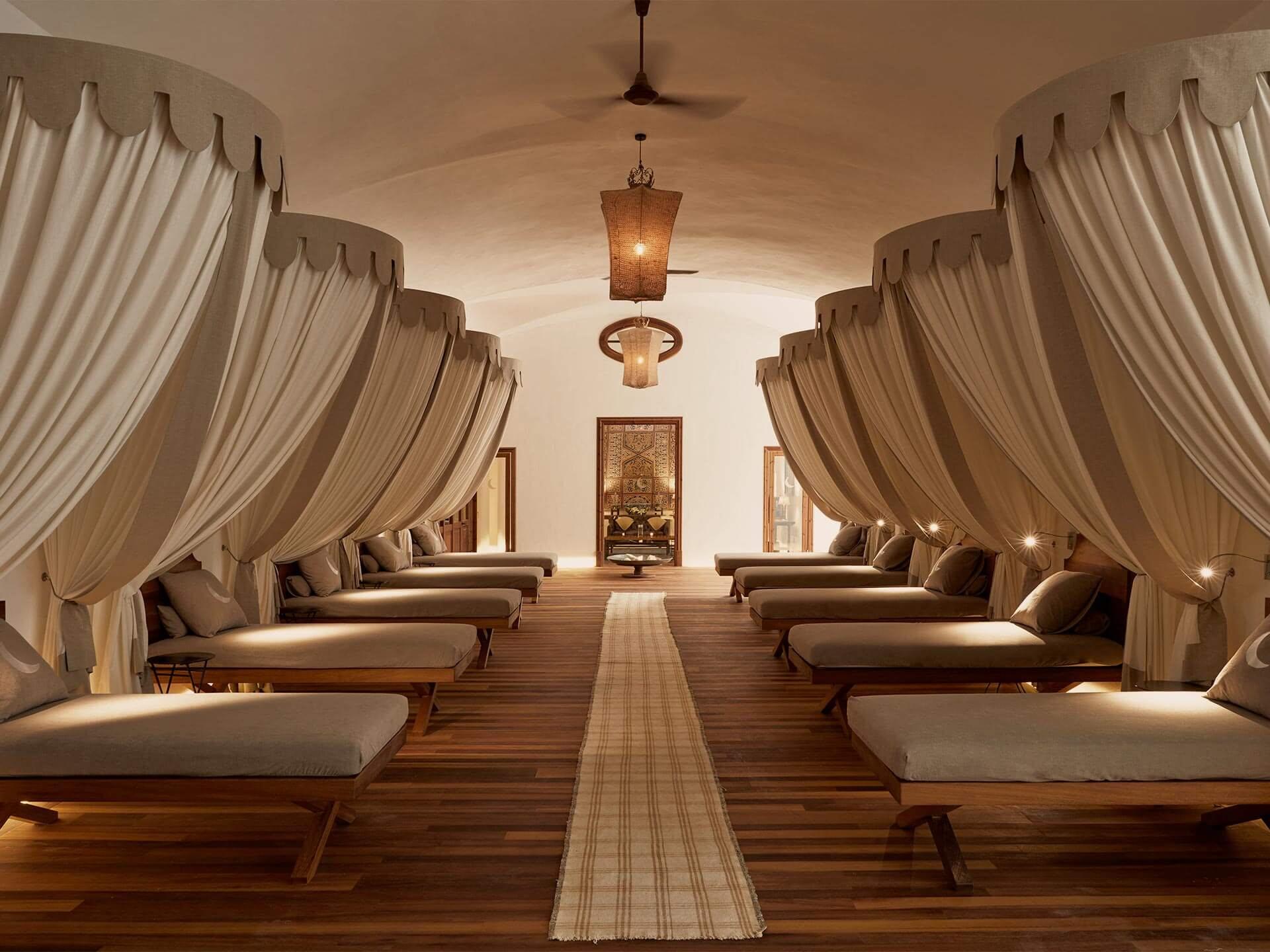 A wellness pavilion lined with cream draped loungers and minimal contemporary furnishings