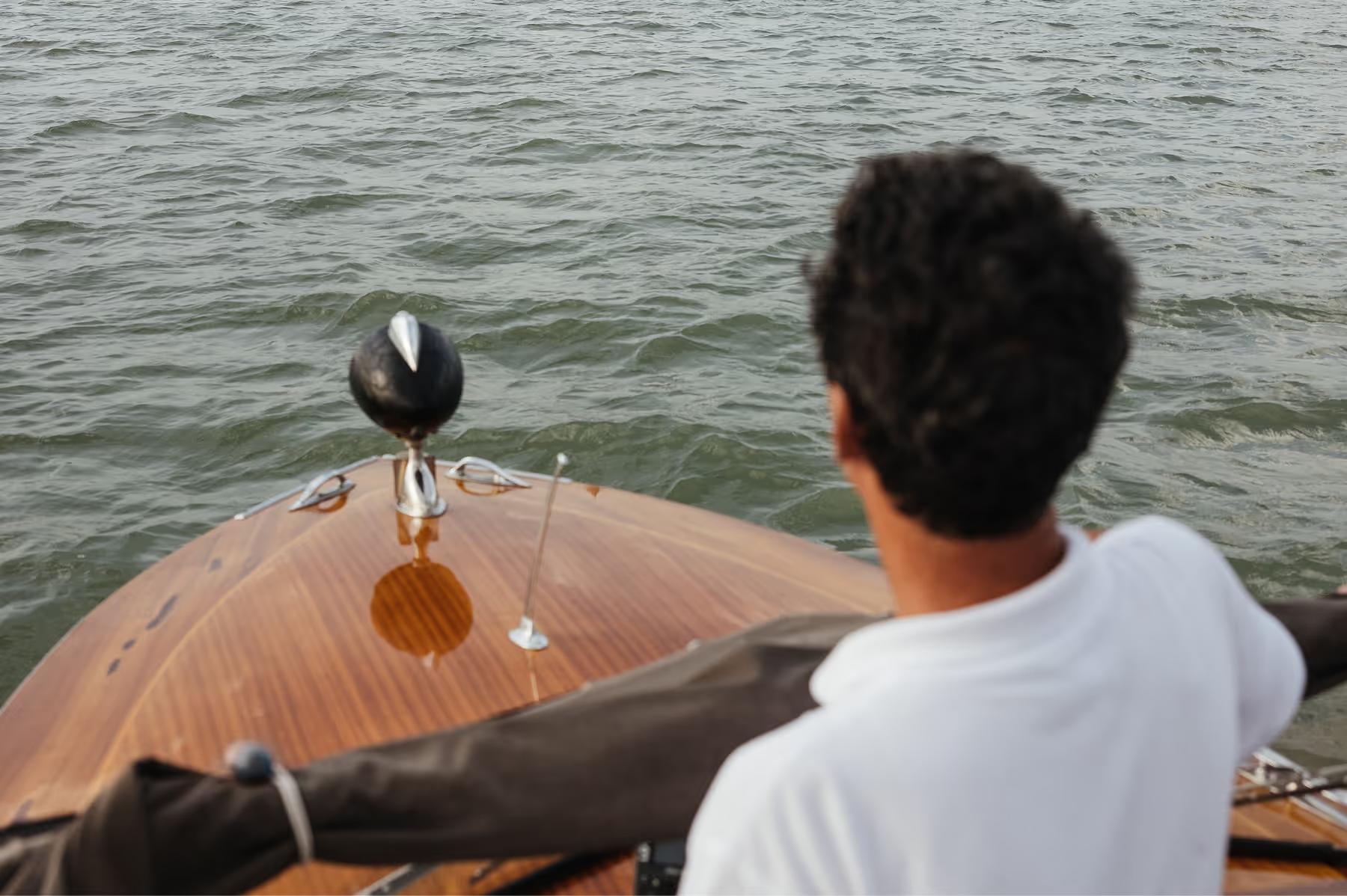 A person in a wooden boat on the Grand Canal, with a gondola pole visible against the water