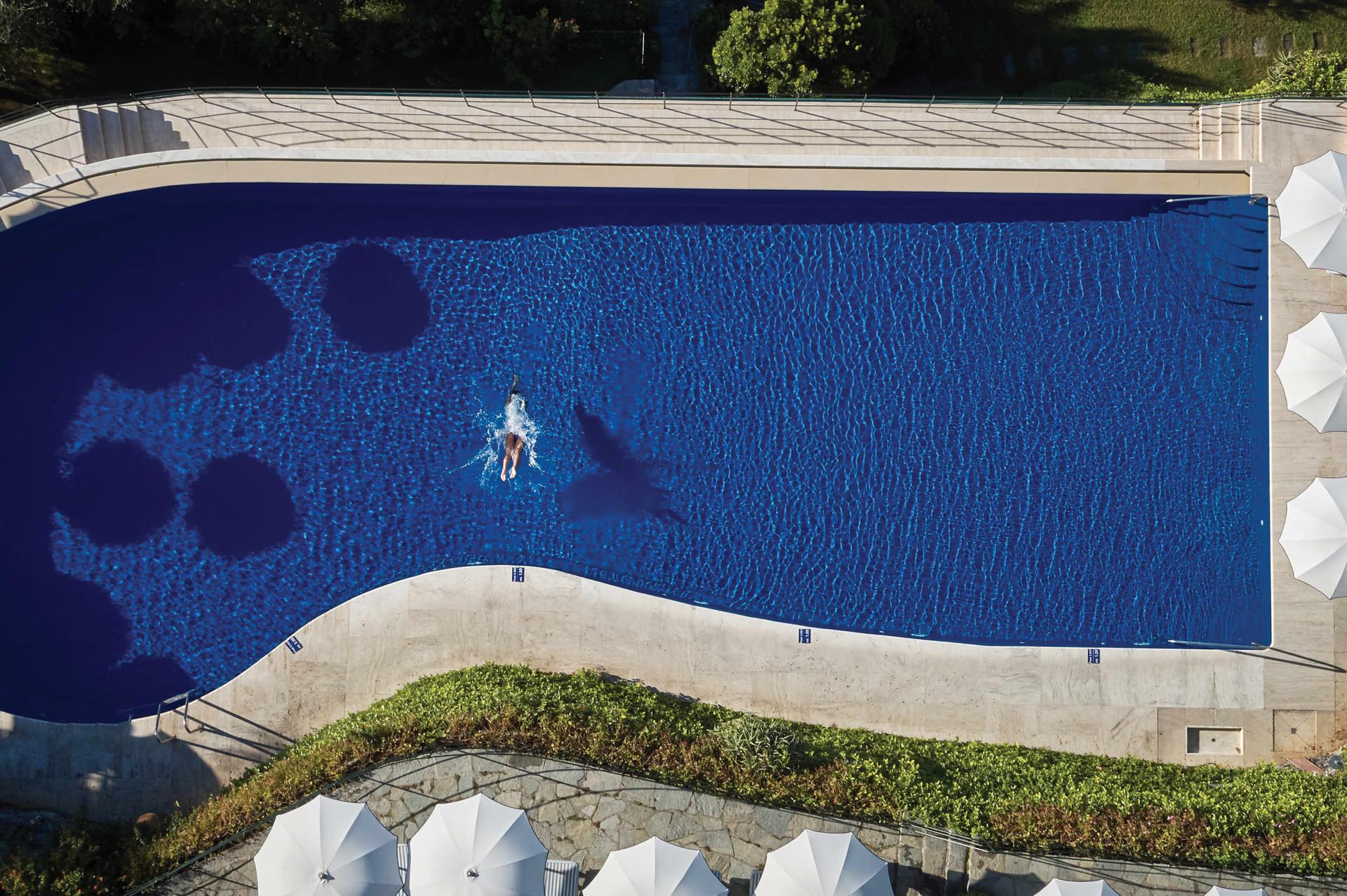 Splendido: an aerial view of the infinity pool with swimmers, surrounded by green lawns