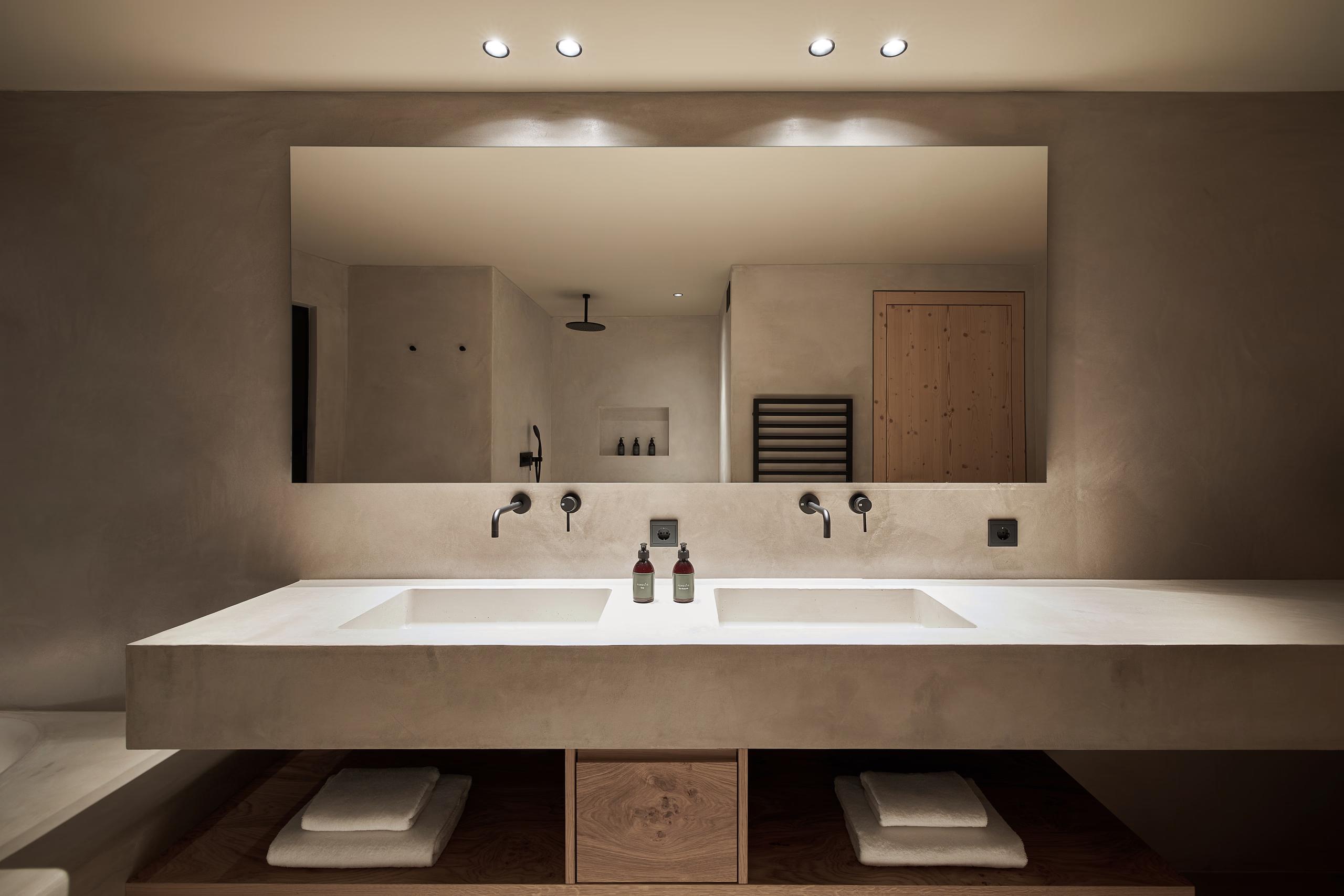 A residential suite entry with modern furnishings, neutral palette, and mountain backdrop through glass