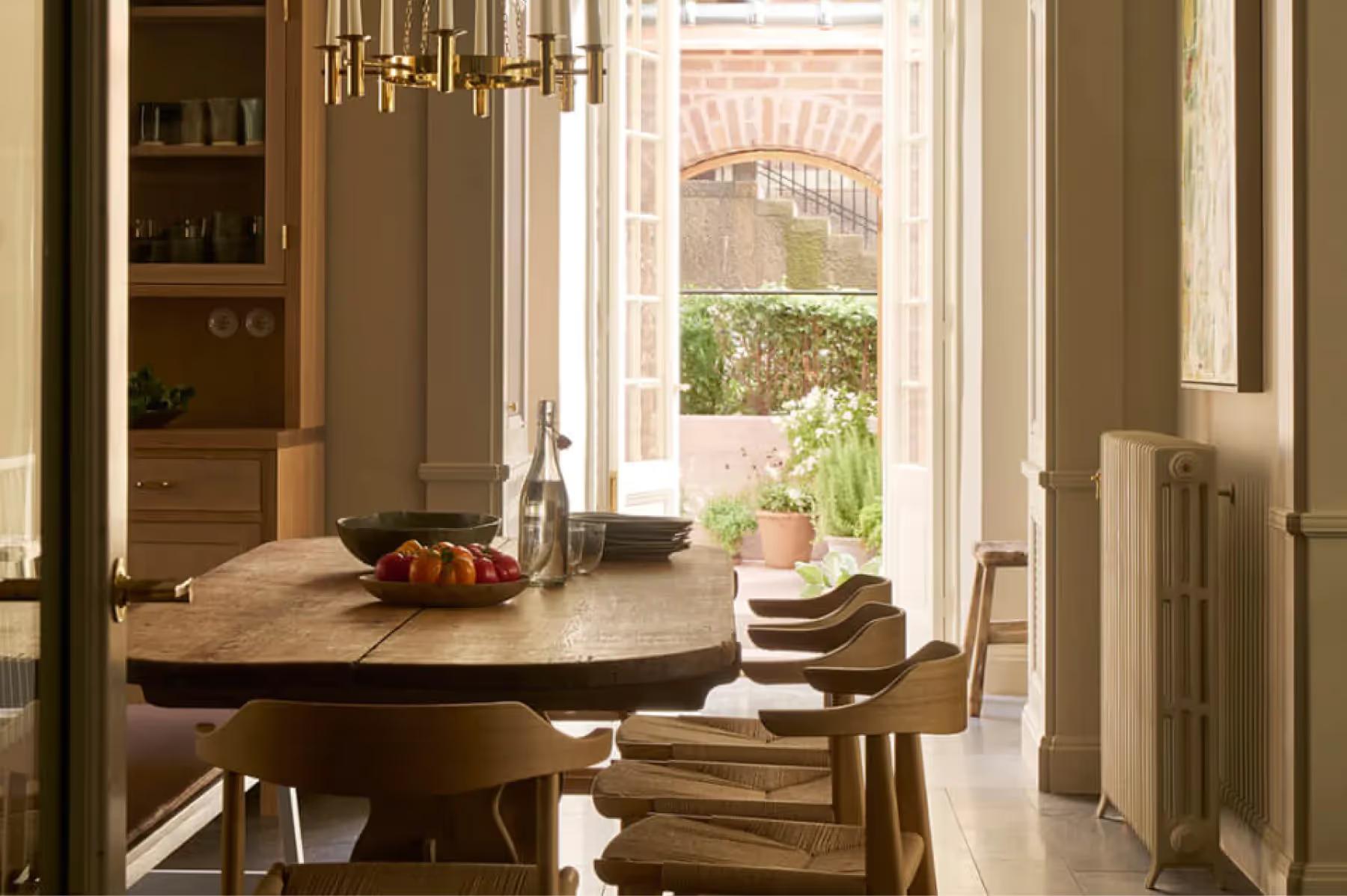 Ett Hem: a round table by tall doors with a garden view and pendant lighting, bookshelf visible
