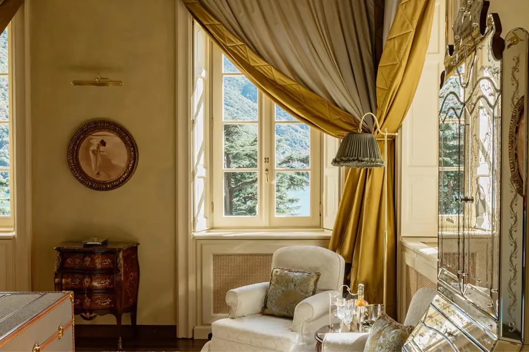 A sitting room with window seating, gold damask curtains, and lake views