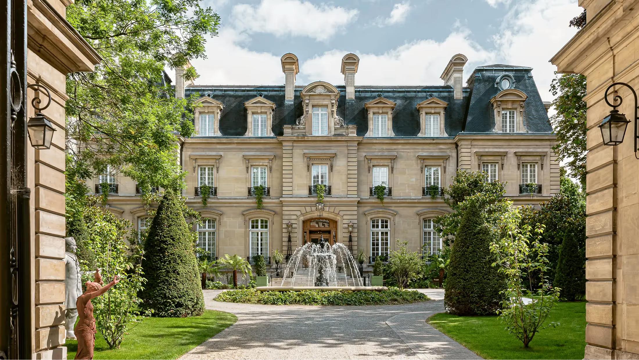 The château facade framed by ivy-draped walls, with a central fountain visible in the courtyard beyond