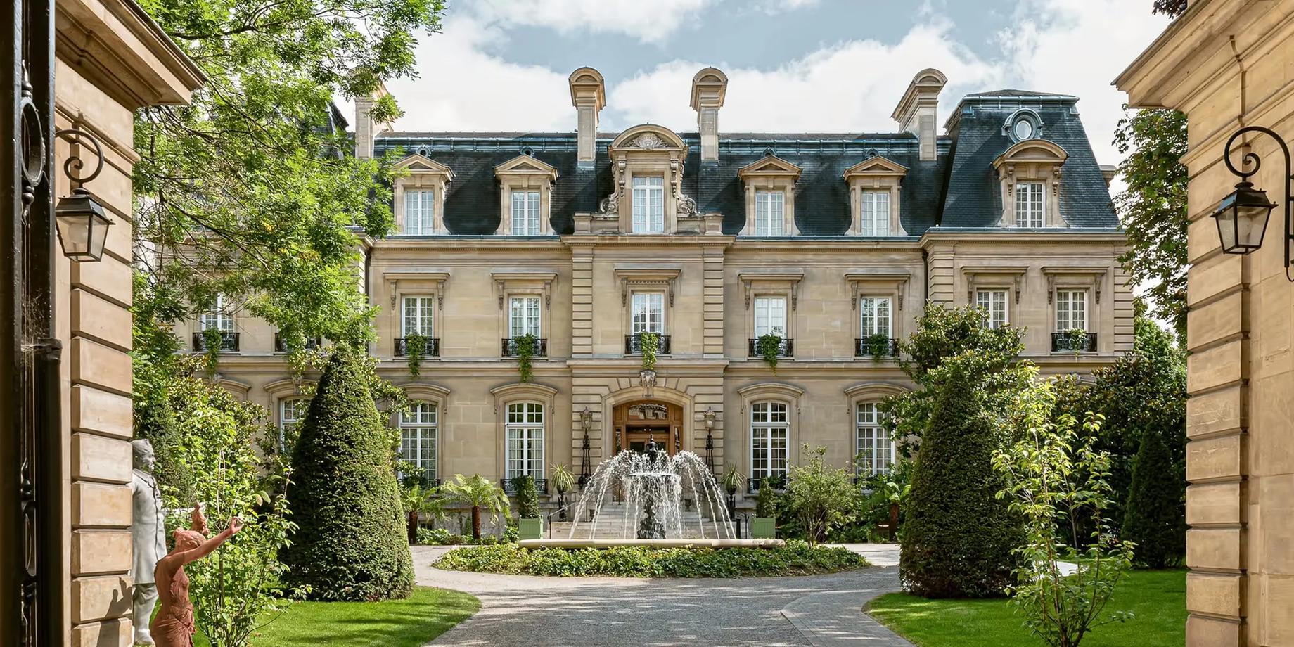 The château facade framed by ivy-draped walls, with a central fountain visible in the courtyard beyond