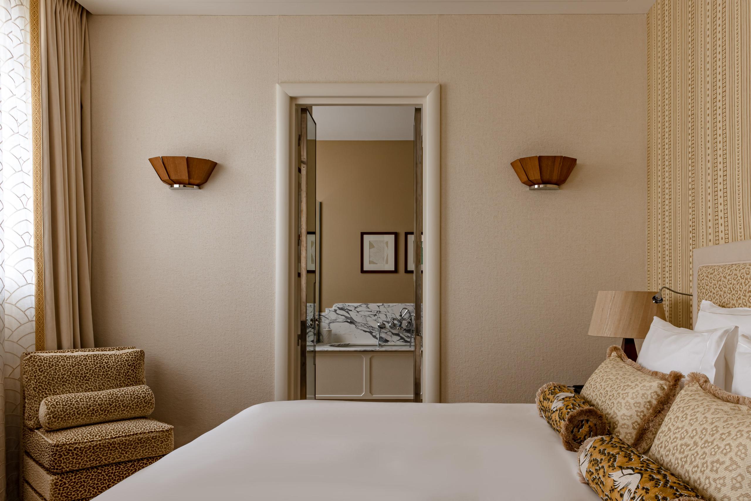 Saint James: bedroom interior with brass double bed, pale upholstery, and dark mirror detailing