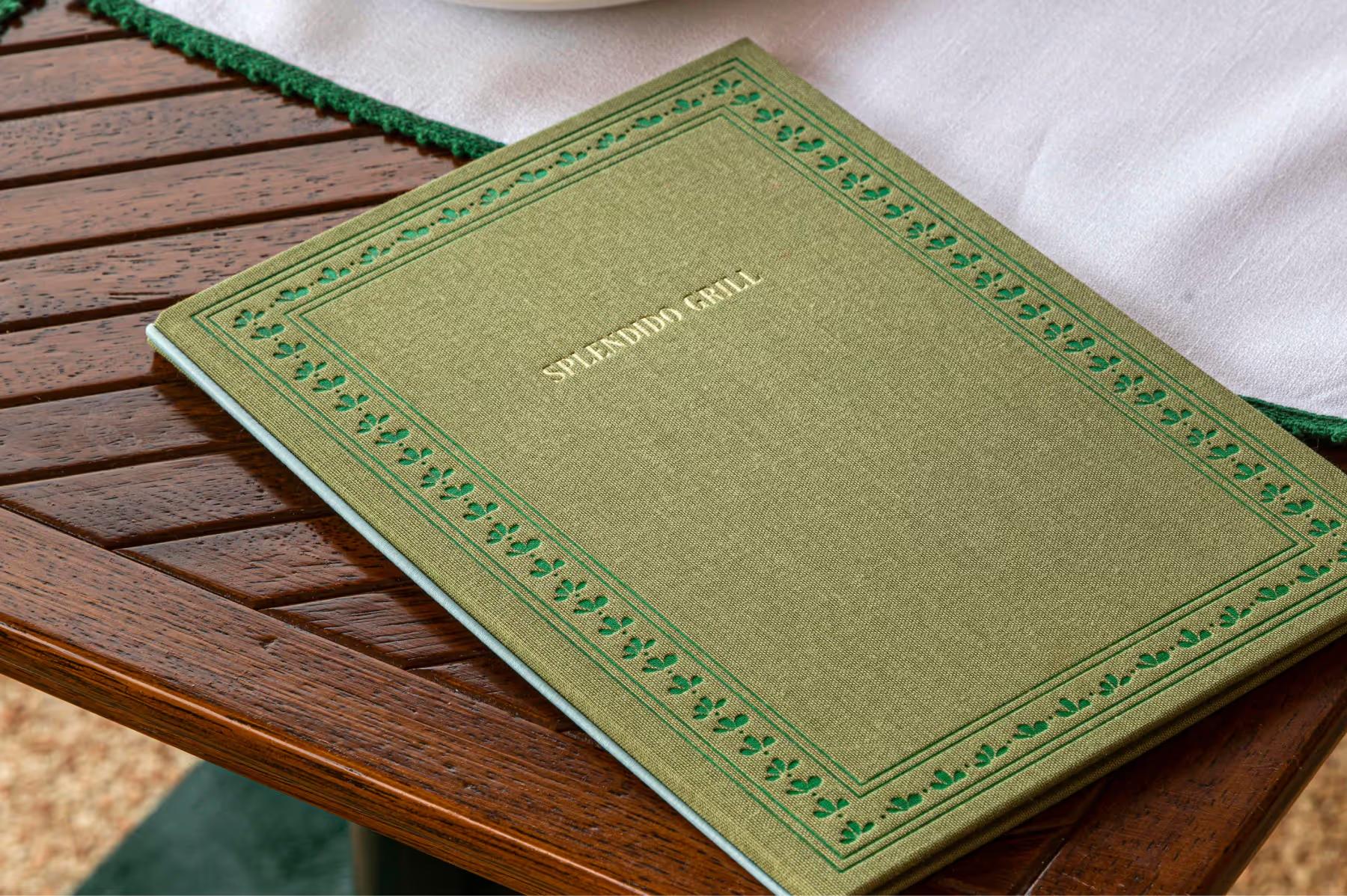 Splendido: a leather-bound restaurant menu on a wooden table by the sea