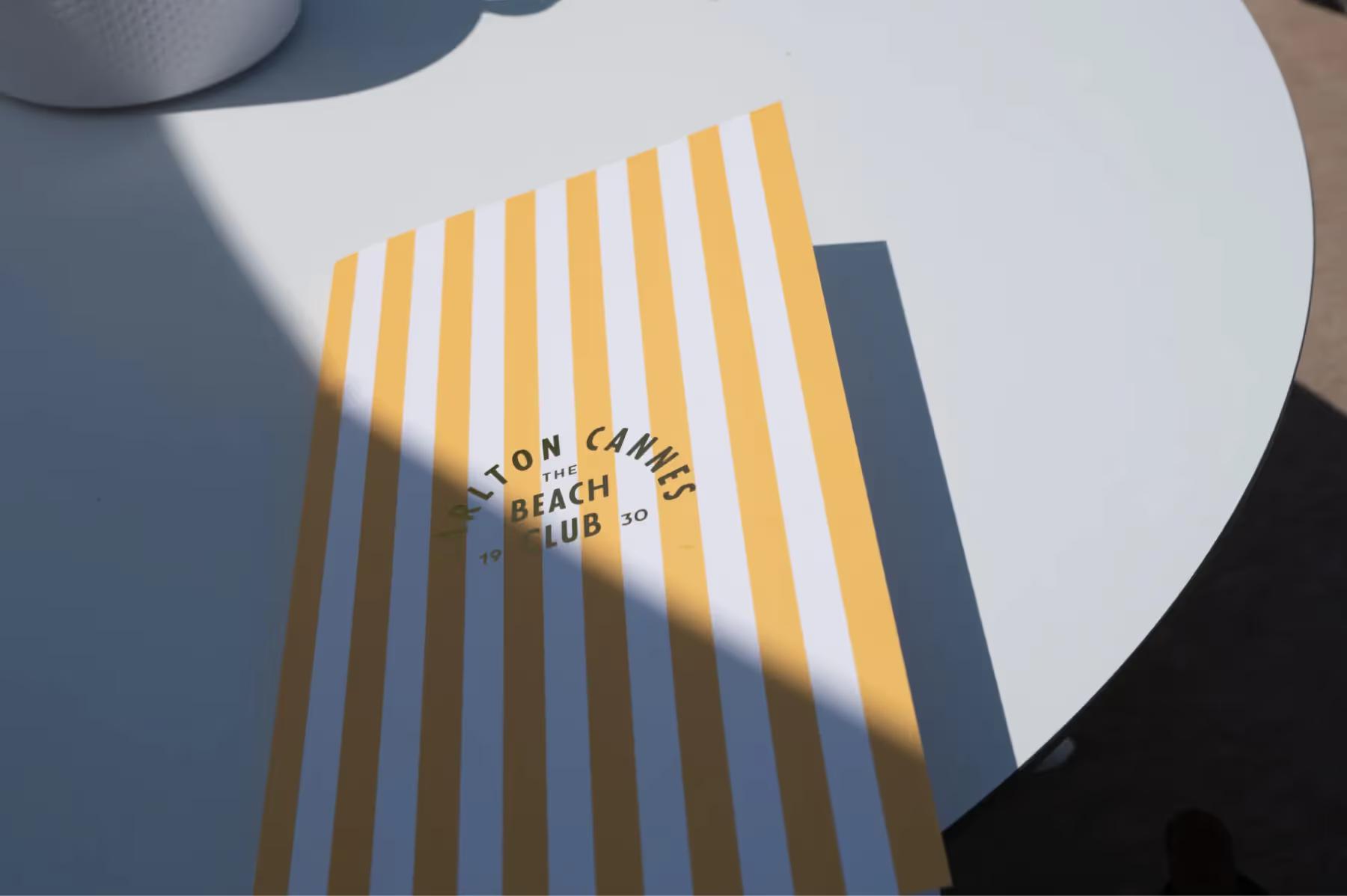 Detail of a white table with yellow striped shadow pattern from overhead structure
