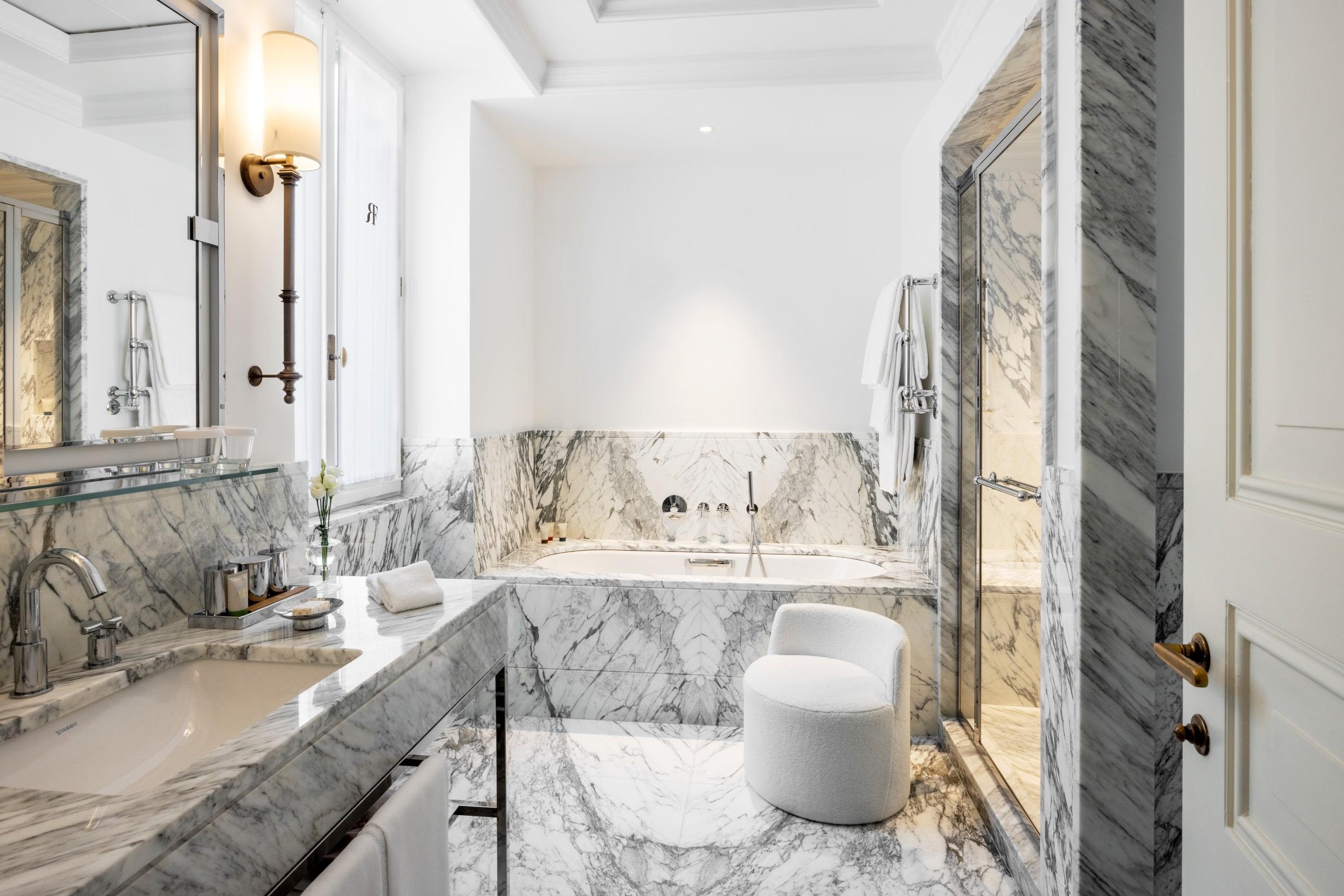 Marble bathroom with dual sinks, decorative panels, and white fixtures