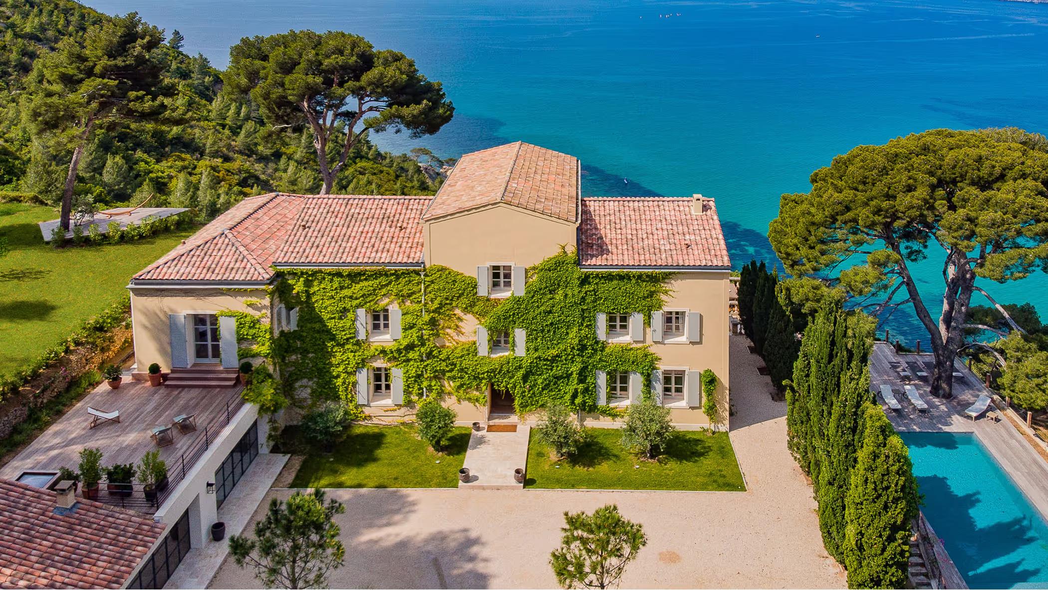 Terracotta villa with clay-tiled roof set on clifftop overlooking turquoise Mediterranean waters