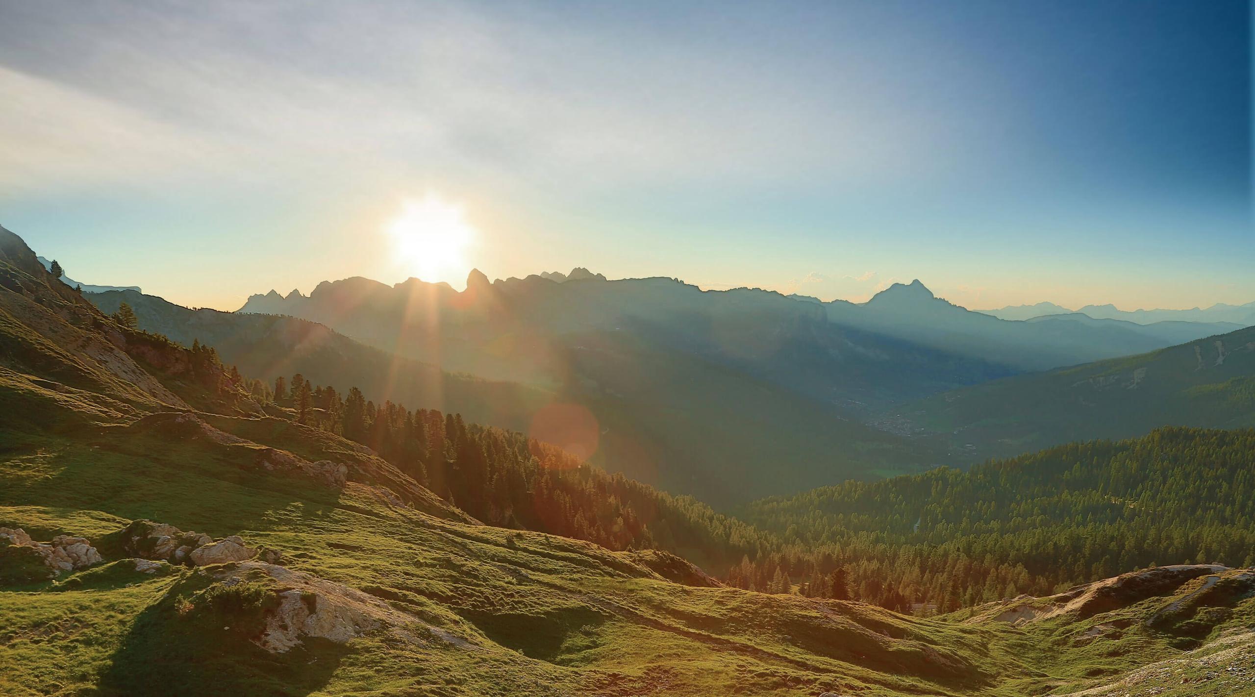 San Luis Retreat: alpine meadow at sunrise with forested mountains and golden light