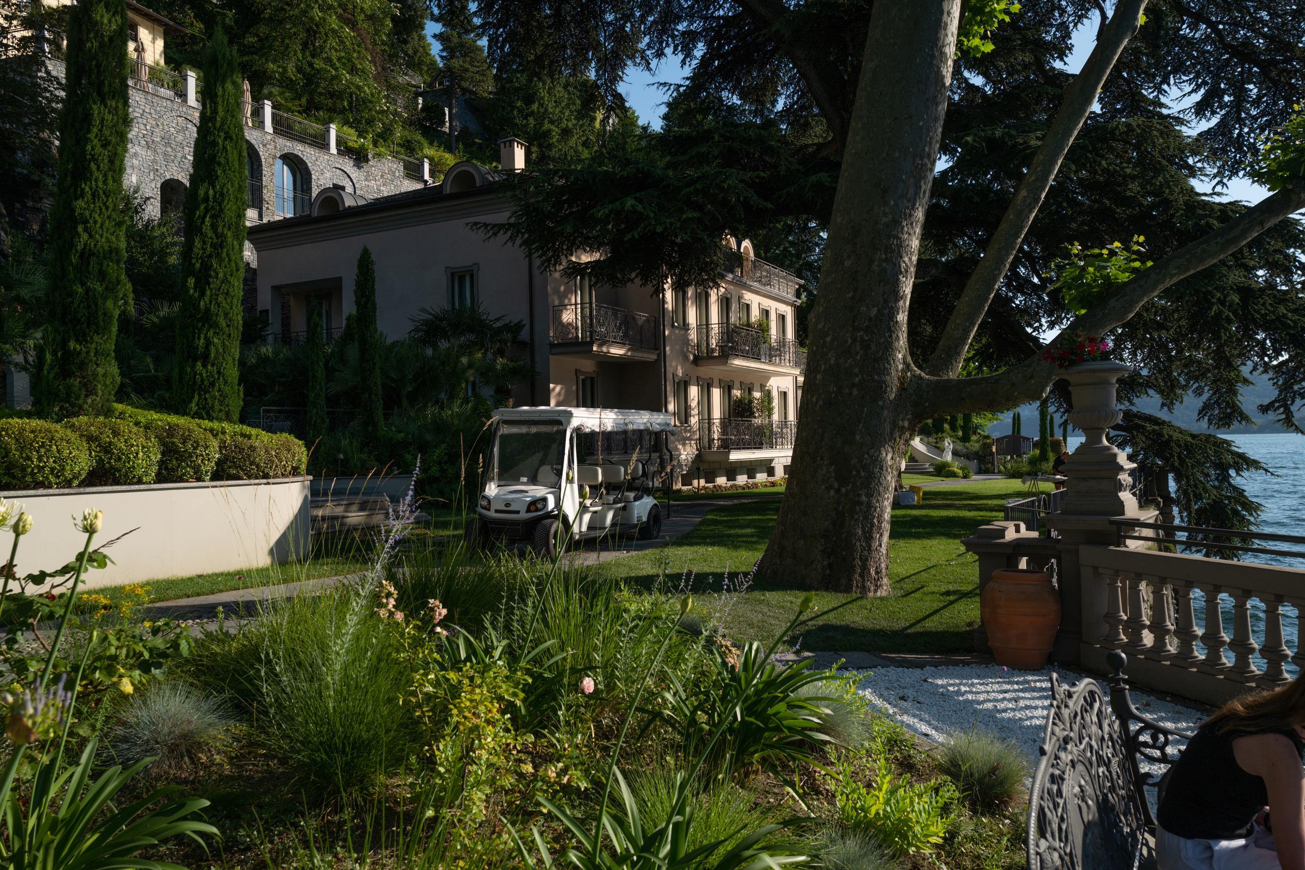Manor grounds with palms, green lawn, stone structures, and terraced architecture