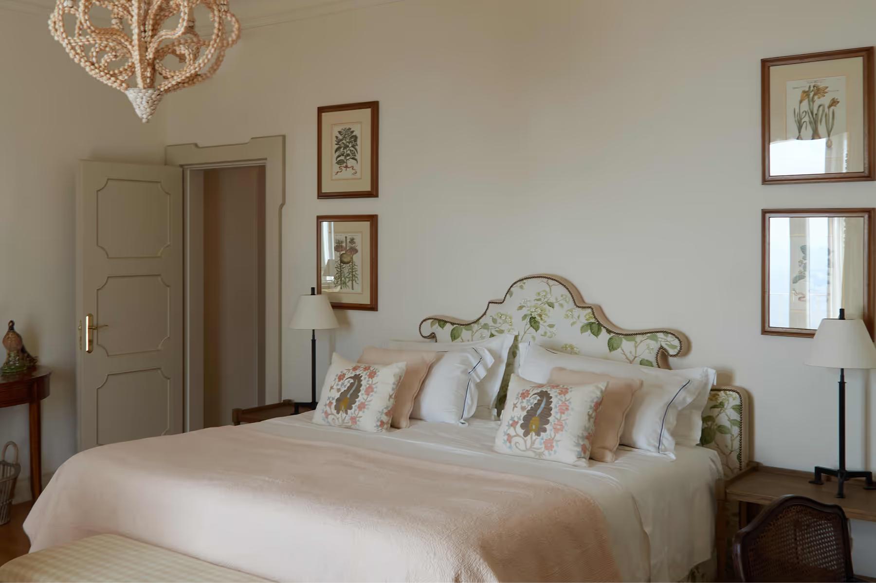 Bedroom with cream walls, ornate brass bed with patterned cushions, framed artwork, and arched niche