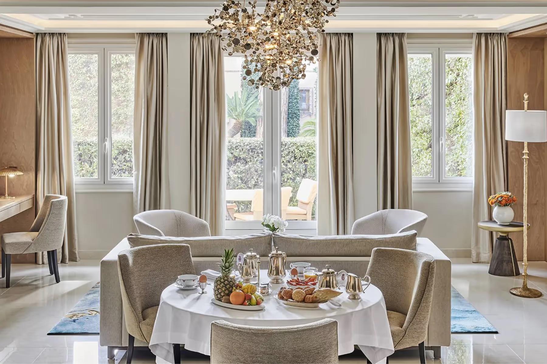 La Réserve de Beaulieu: elegant salon with multiple armchairs arranged around a central table, brass and marble accents