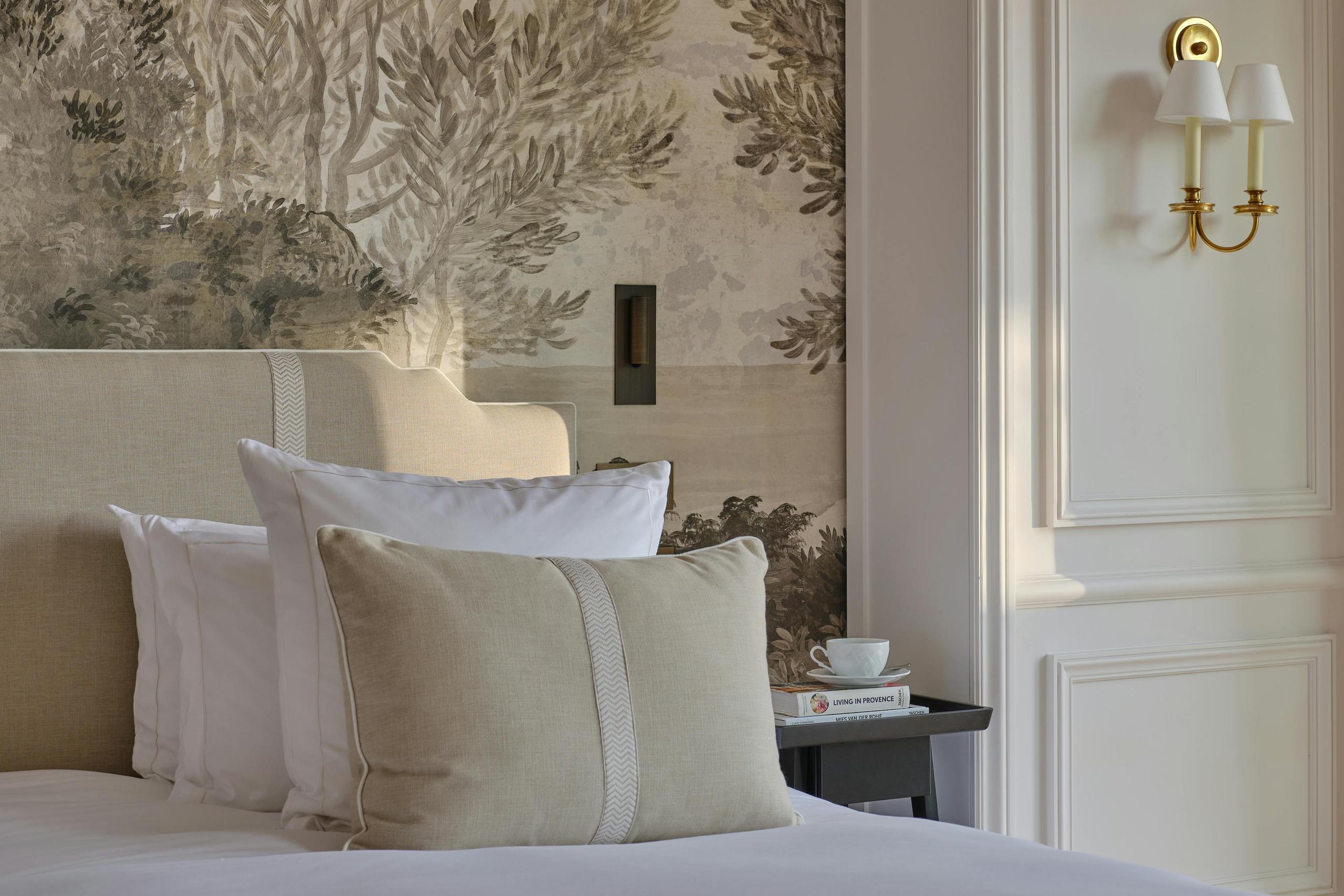Bedroom with paneled headboard wall, white linens, and gold wall sconces