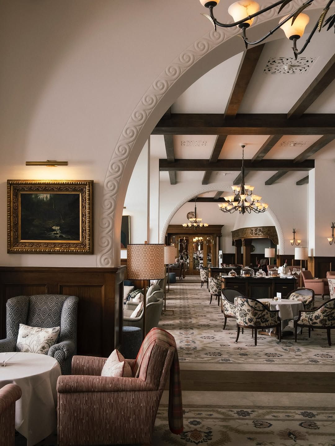 A grand arched lounge with paintings, armchairs, and chandeliers in St. Moritz