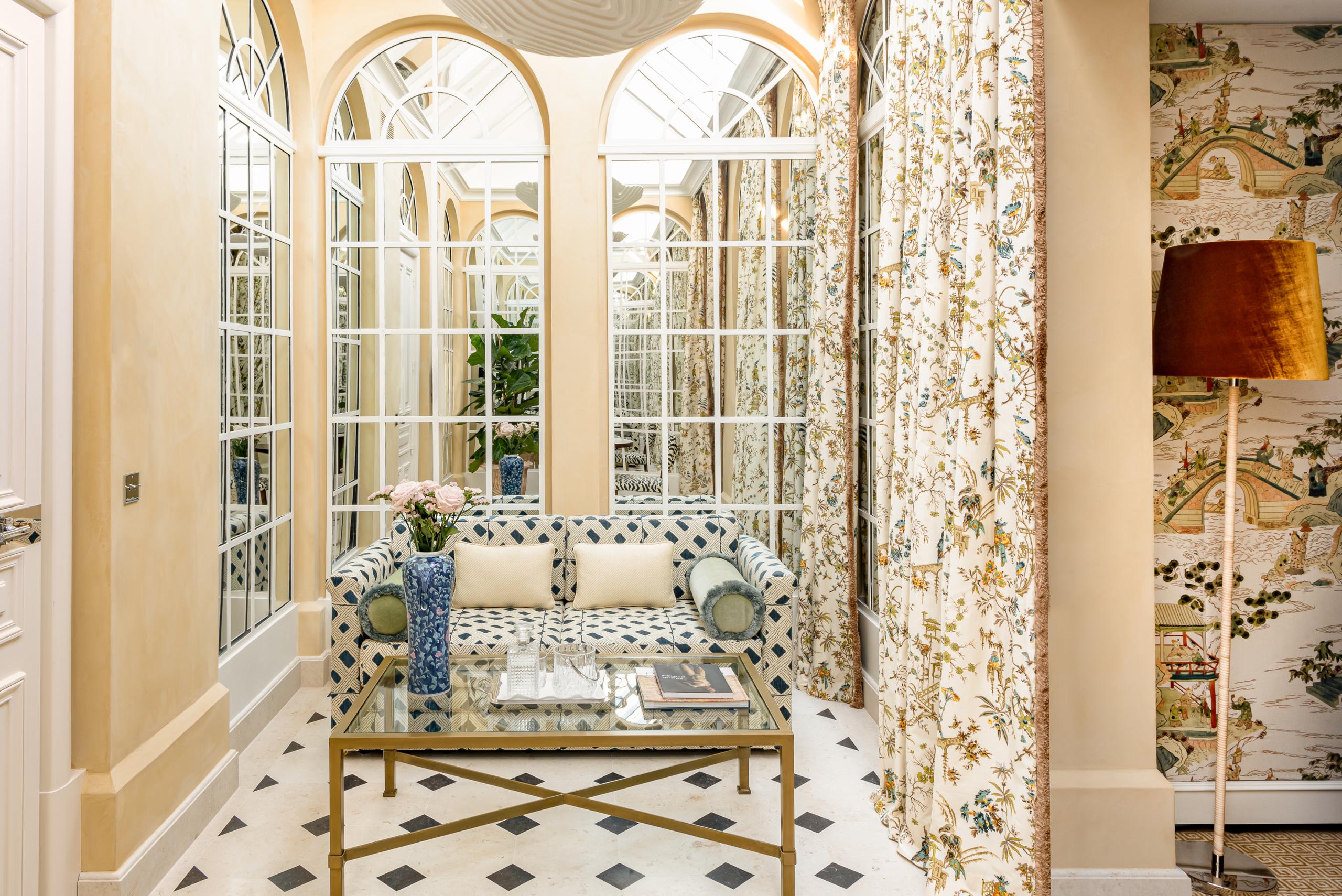 Glass-enclosed patio room with geometric pattern furnishings, arched transom windows