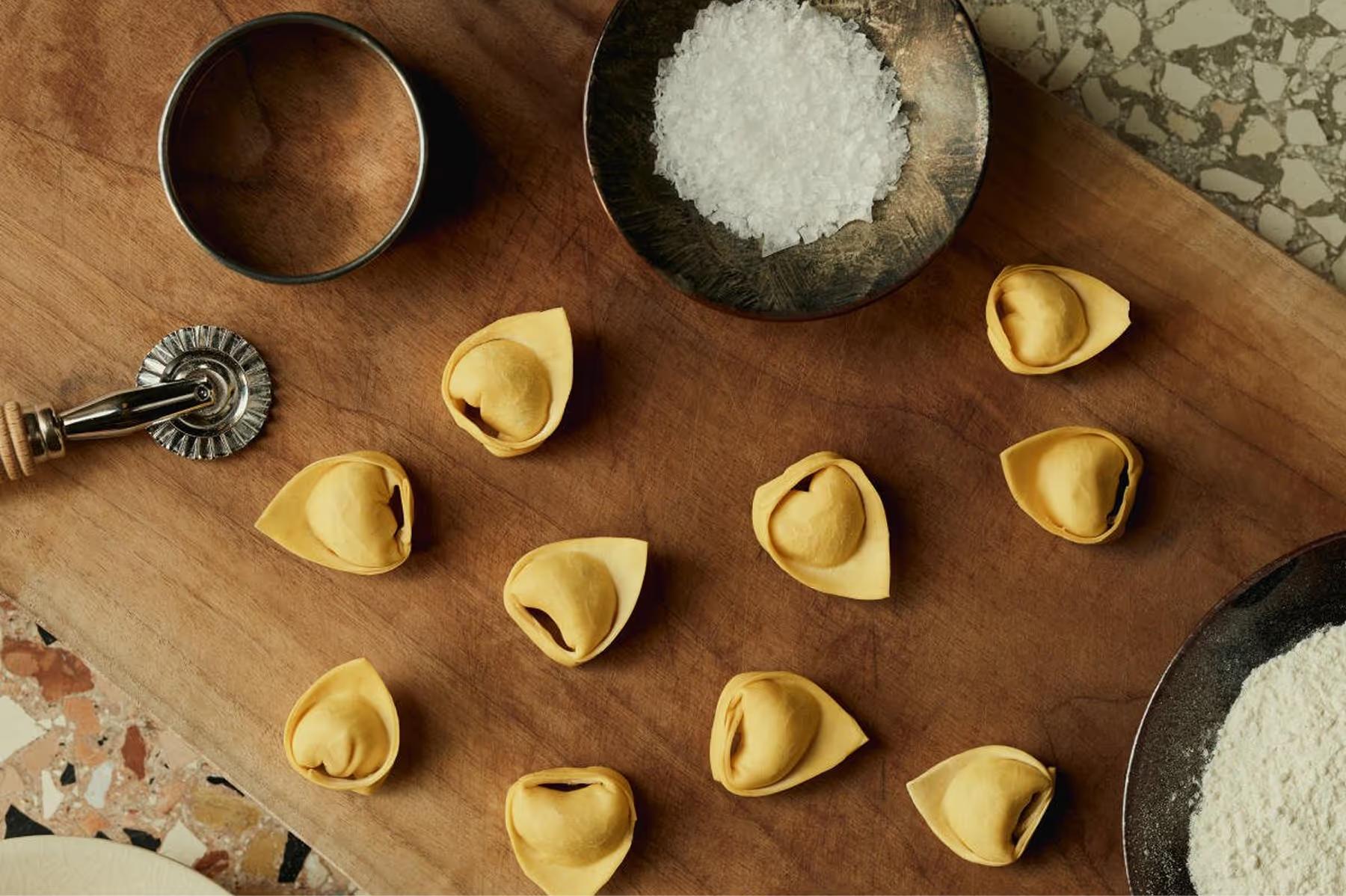 Aman Venice: handmade pasta arranged on a wooden board with flour and salt, artisanal food preparation