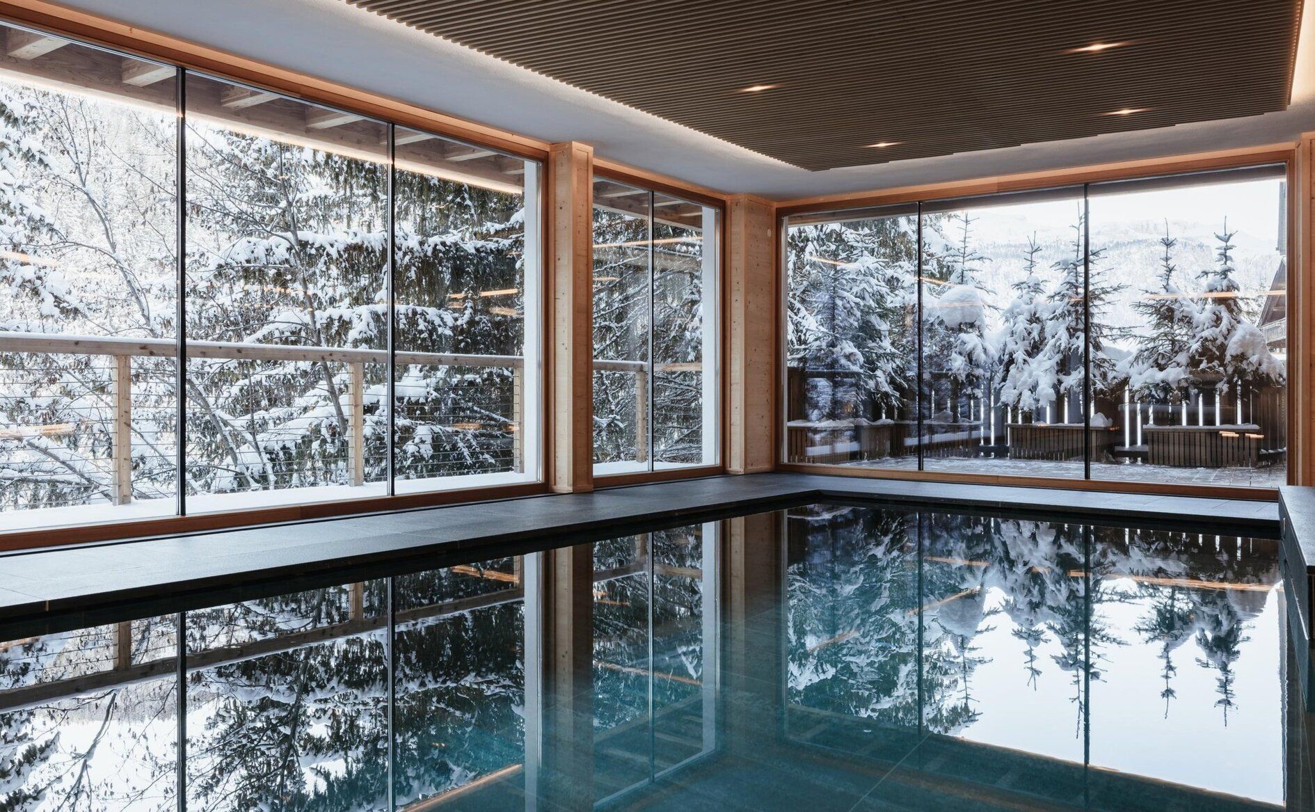 The indoor pool at Aman Rosa Alpina with windows onto snow-covered forest