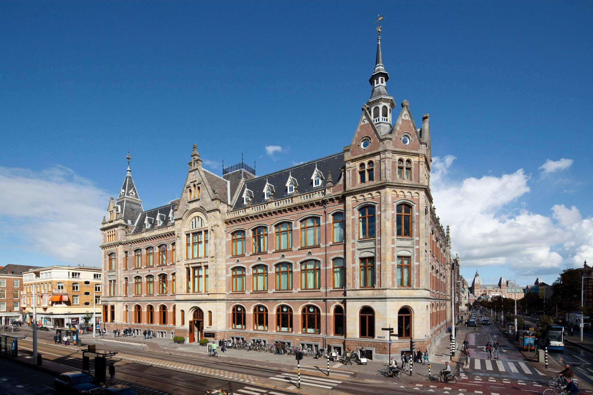 Mandarin Oriental Conservatorium, Amsterdam: corner of the hotel building and its spired tower, beside a wide street with tram tracks and bicycles