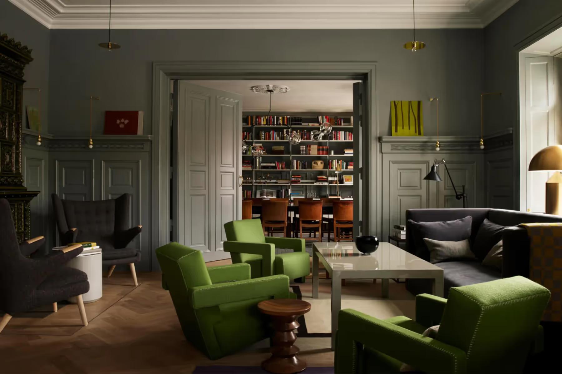 Ett Hem: a library lounge with dark green armchairs, built-in bookshelves, art deco details, and reading lamps