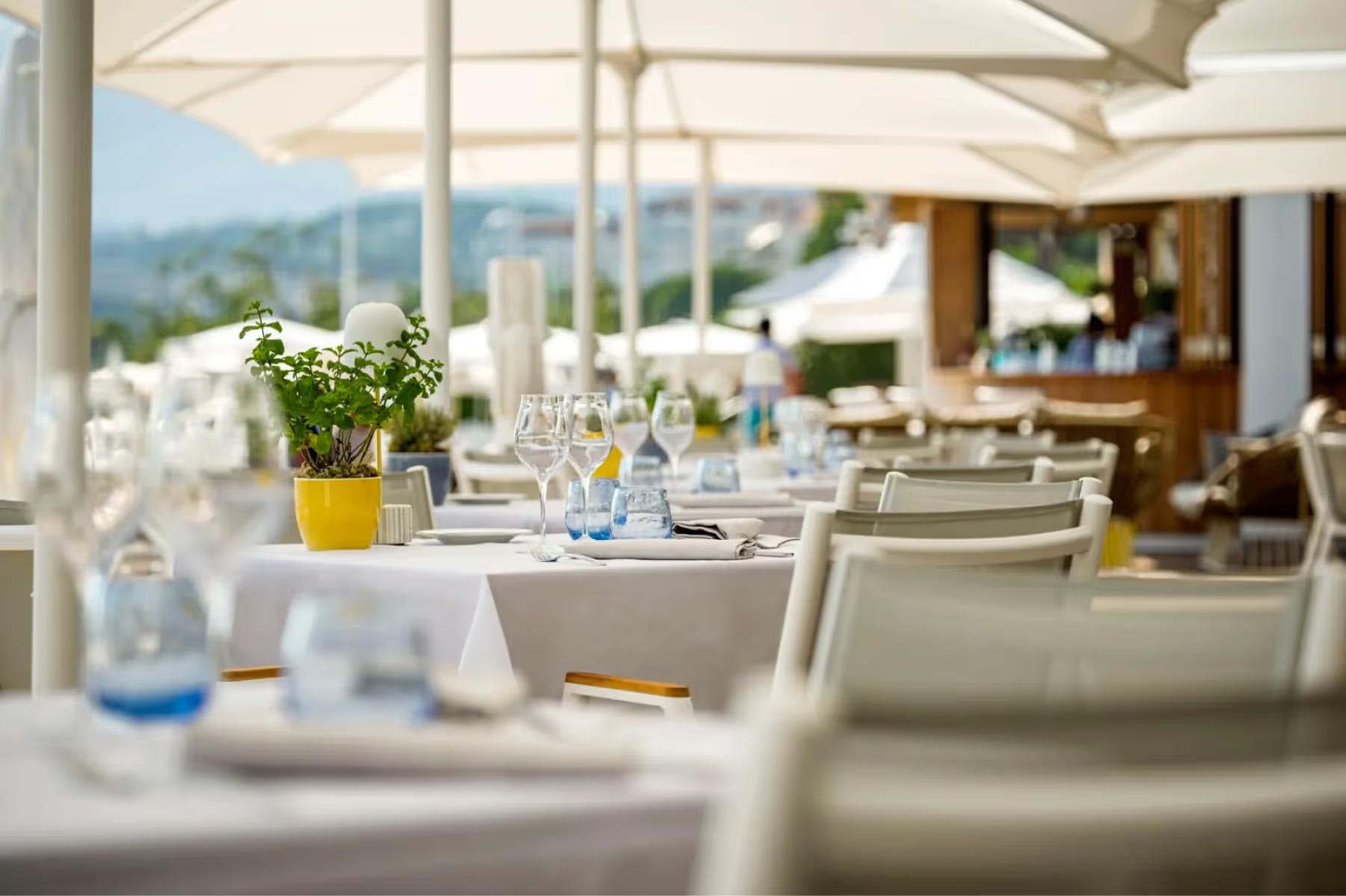 Dining table setup with white linens and a yellow flower arrangement overlooking mountain and sea views