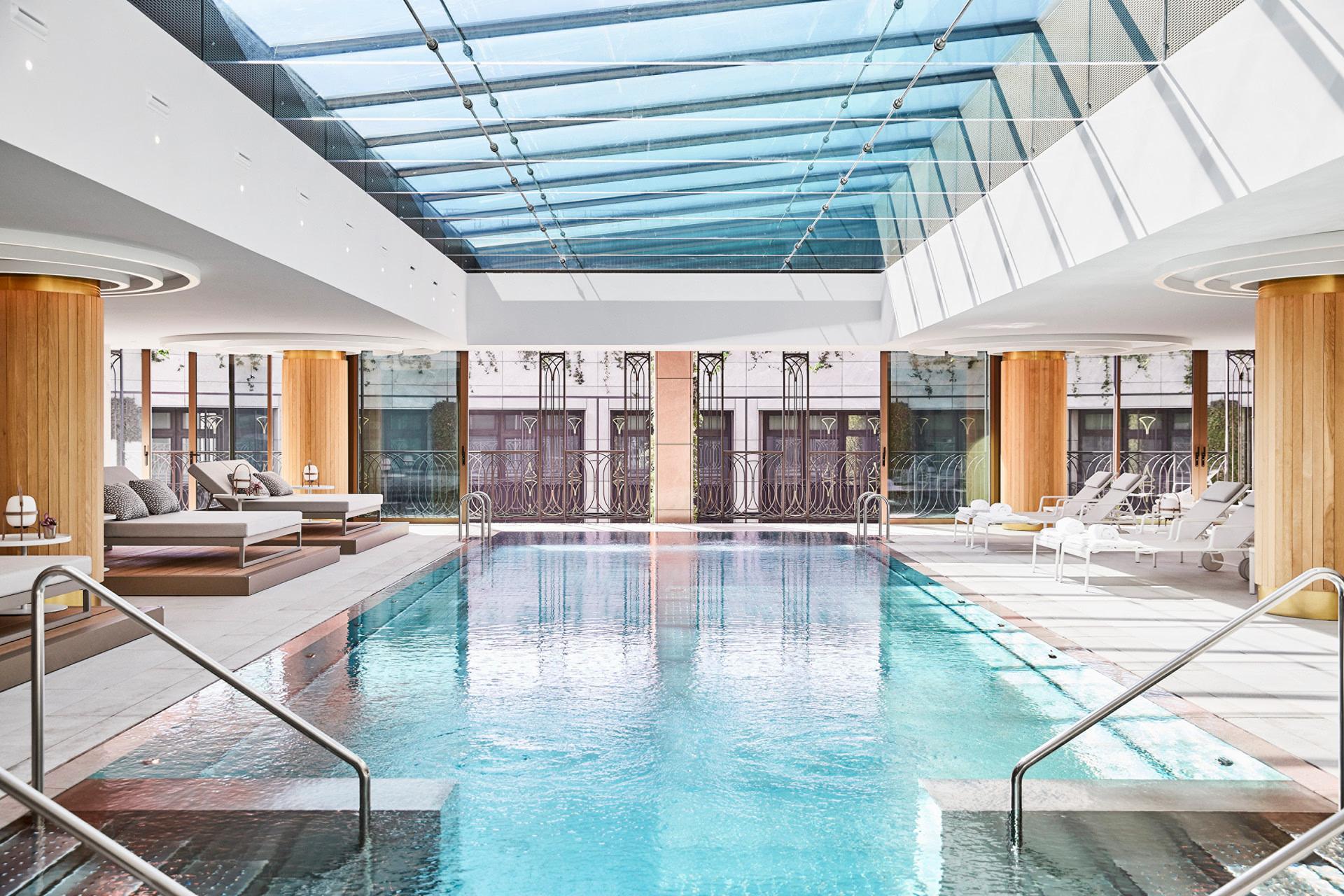 Four Seasons Hotel Madrid: indoor pool with glass skylight ceiling, white wood paneling, and lounging areas on both sides