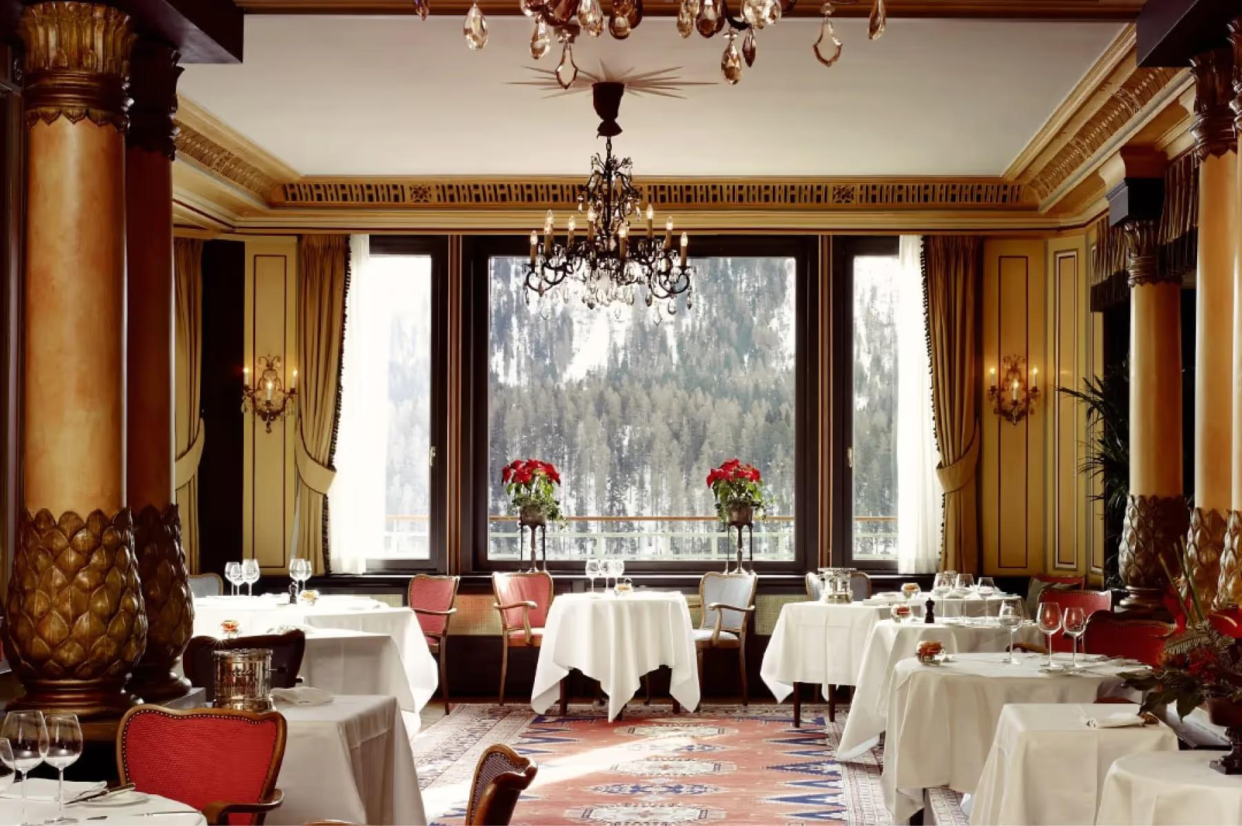 Wooden restaurant interior with open kitchen, chefs at work, and checkered tablecloths