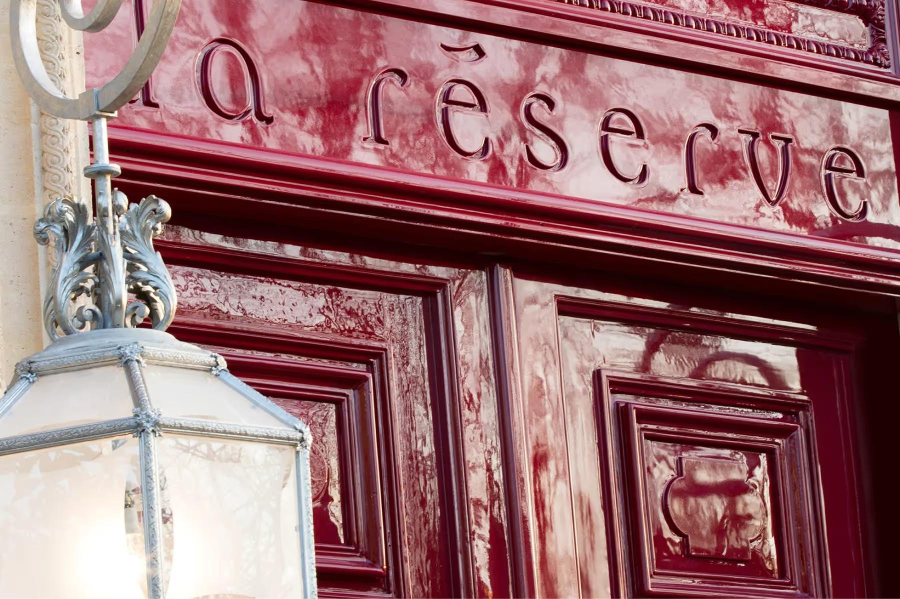 La Réserve Paris: a closeup of the burgundy entrance door with the hotel name in script