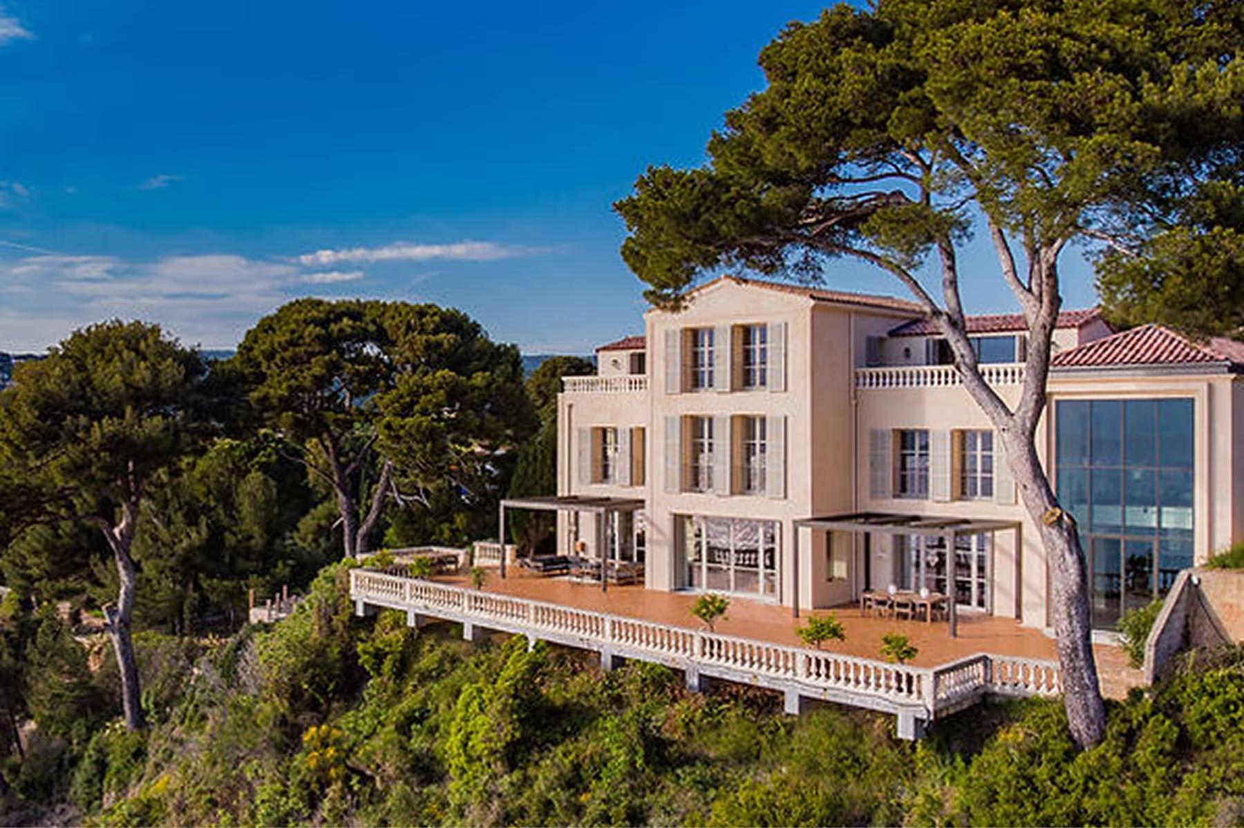 Le Domaine de Canaille: pale stone manor on cliff overlooking bright blue Mediterranean waters and tree-covered slopes