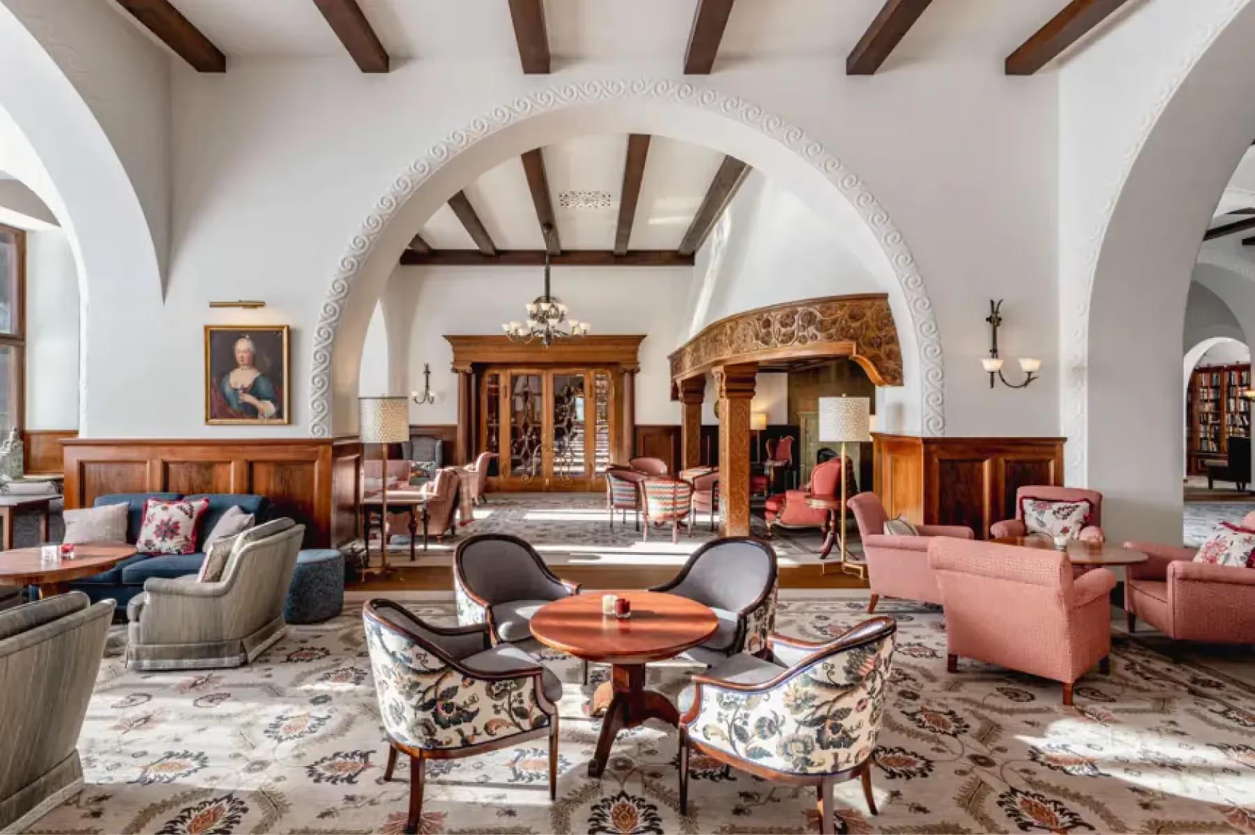The main lounge with arched ceilings, wooden beams, classical furnishings, and garden views