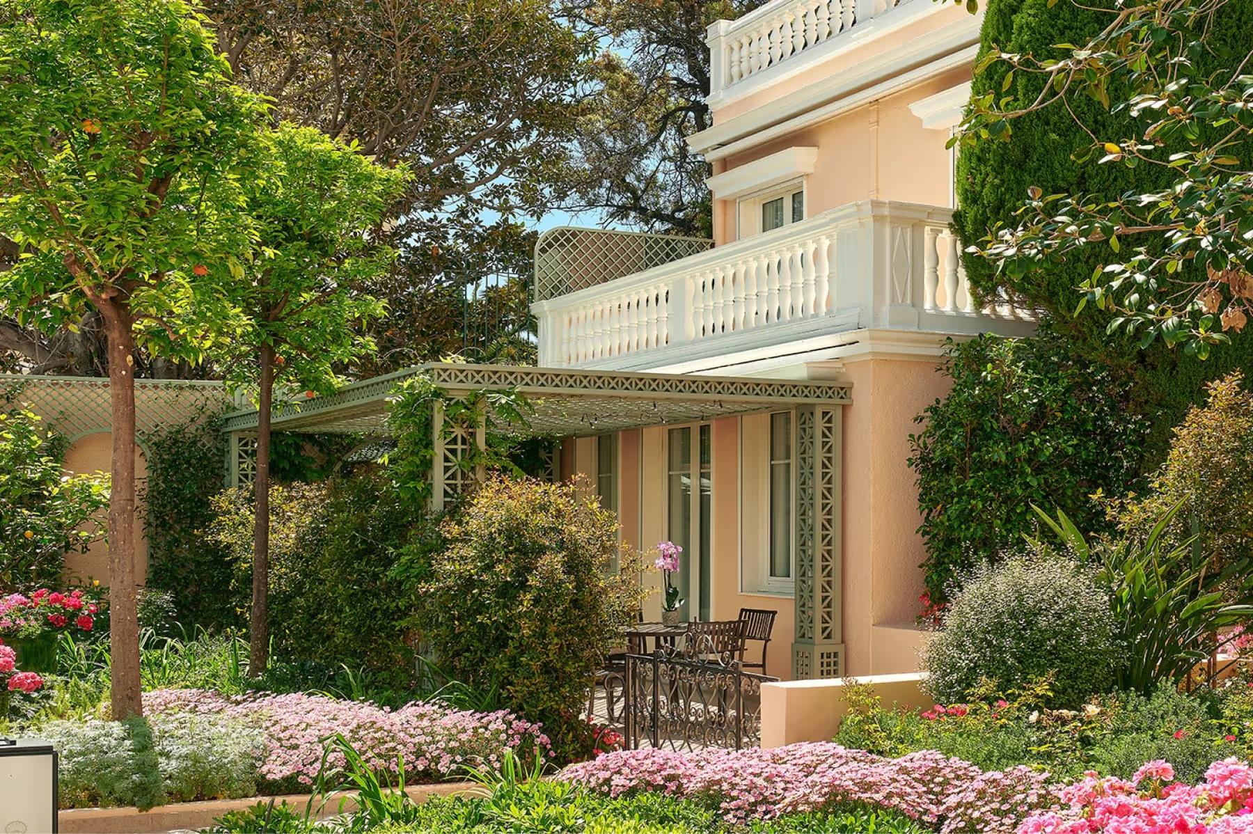 La Réserve de Beaulieu: exterior villa entrance surrounded by blooming pink and white flowers