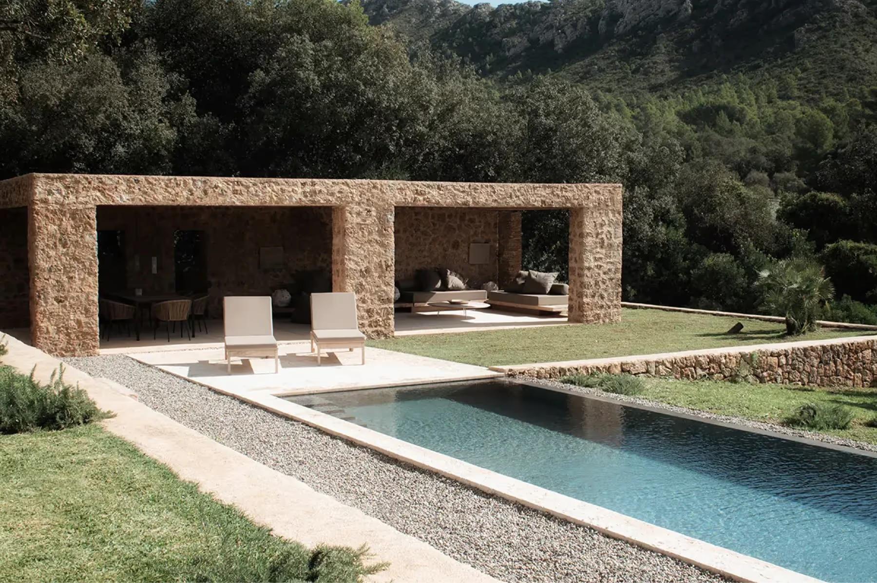 Es Racó d’Artà: stone pavilion structure with open walls framing a swimming pool in manicured estate garden