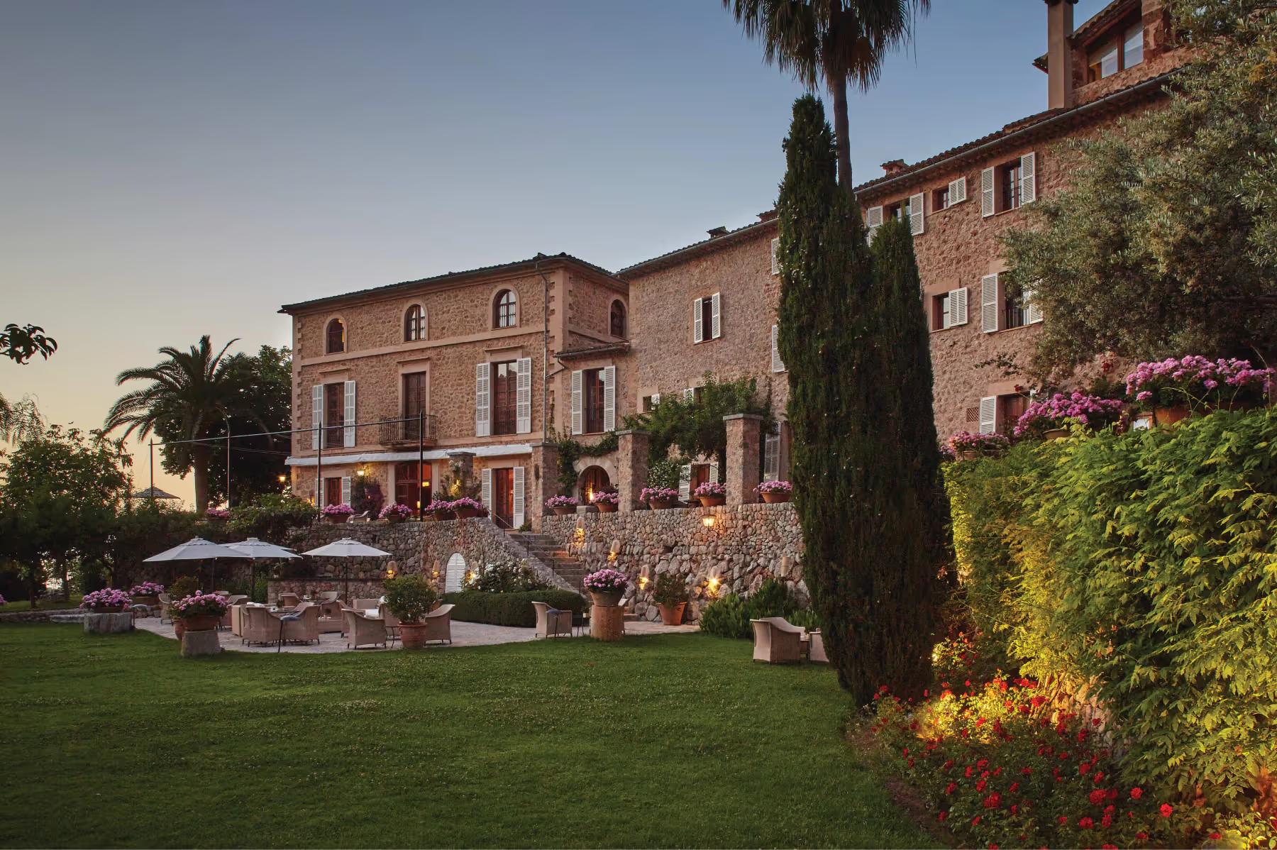 La Residencia: estate buildings in evening light with manicured grounds, cypress trees, and palm tree