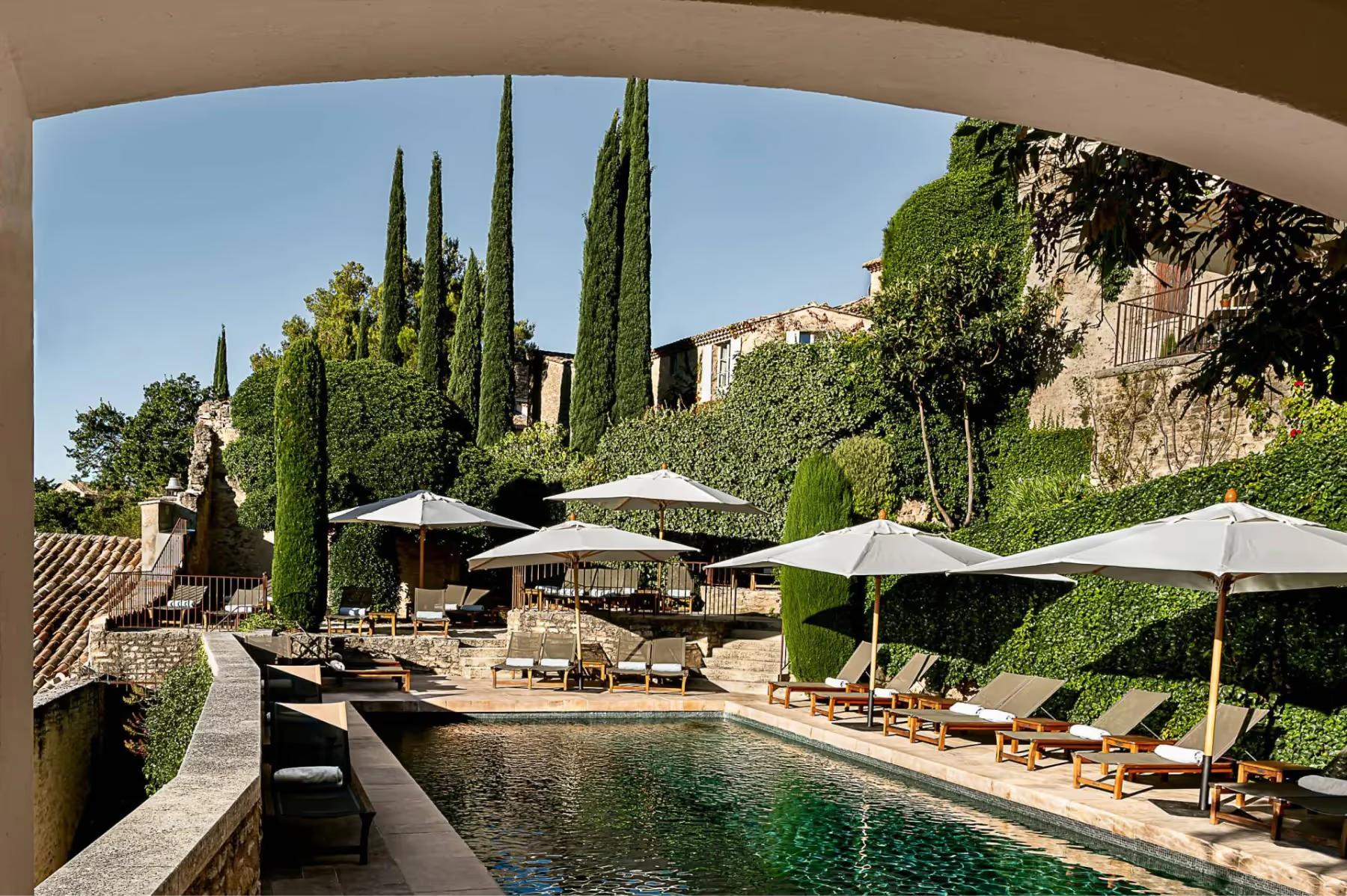 Hôtel Crillon le Brave: a loggia framing the pool terrace, cypress trees, and distant hills under blue sky