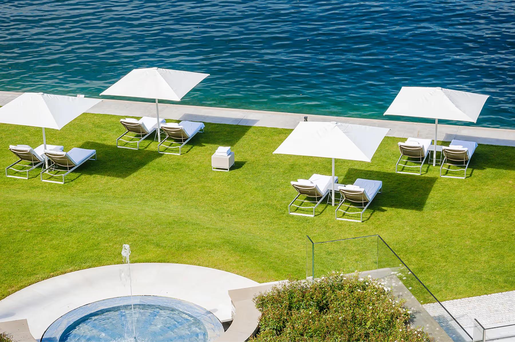 Park Hotel Vitznau: manicured lawn with white lounge chairs and turquoise water