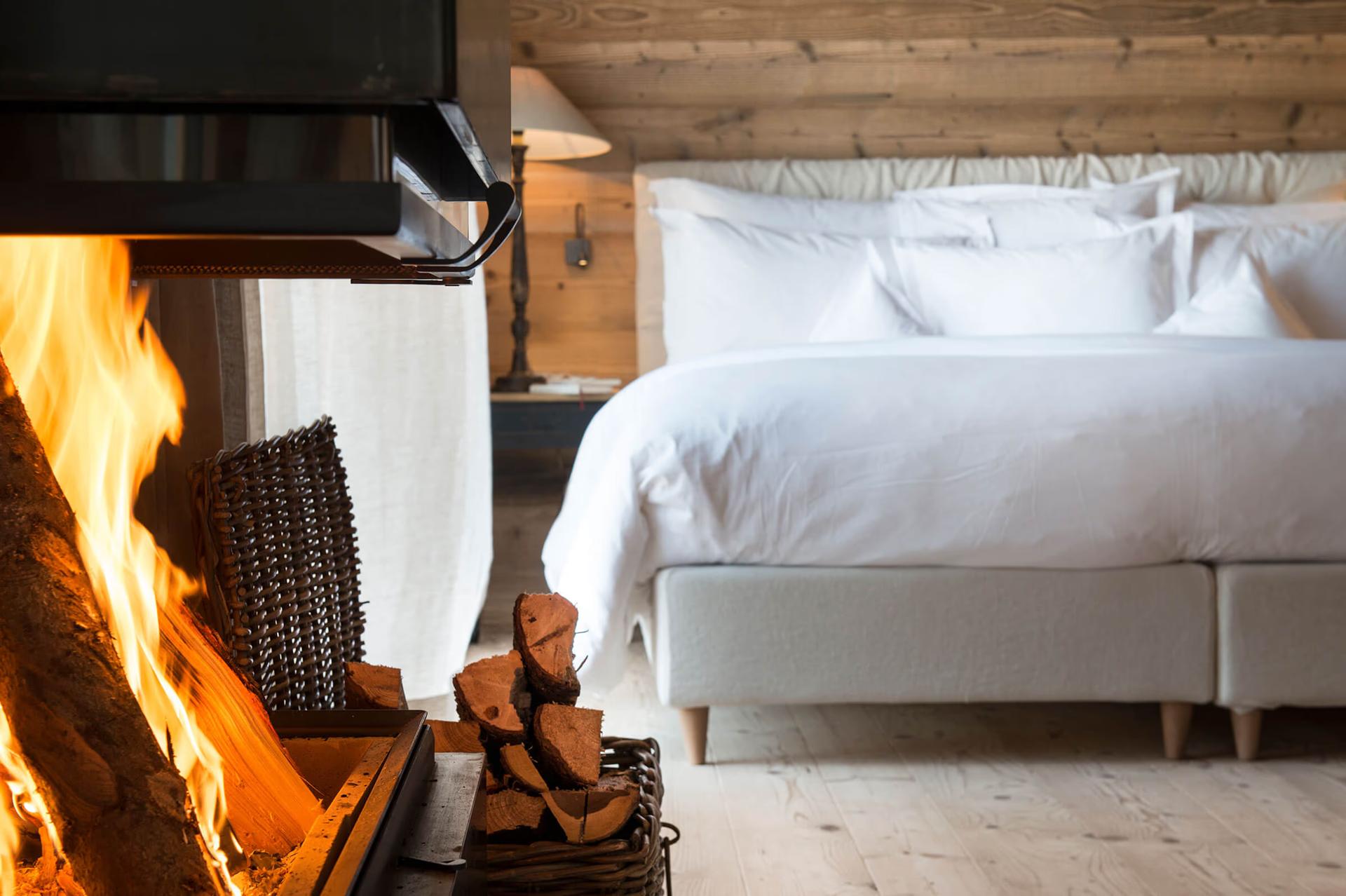 San Luis Retreat: fireplace with roaring flames beside a bed in a wooden room