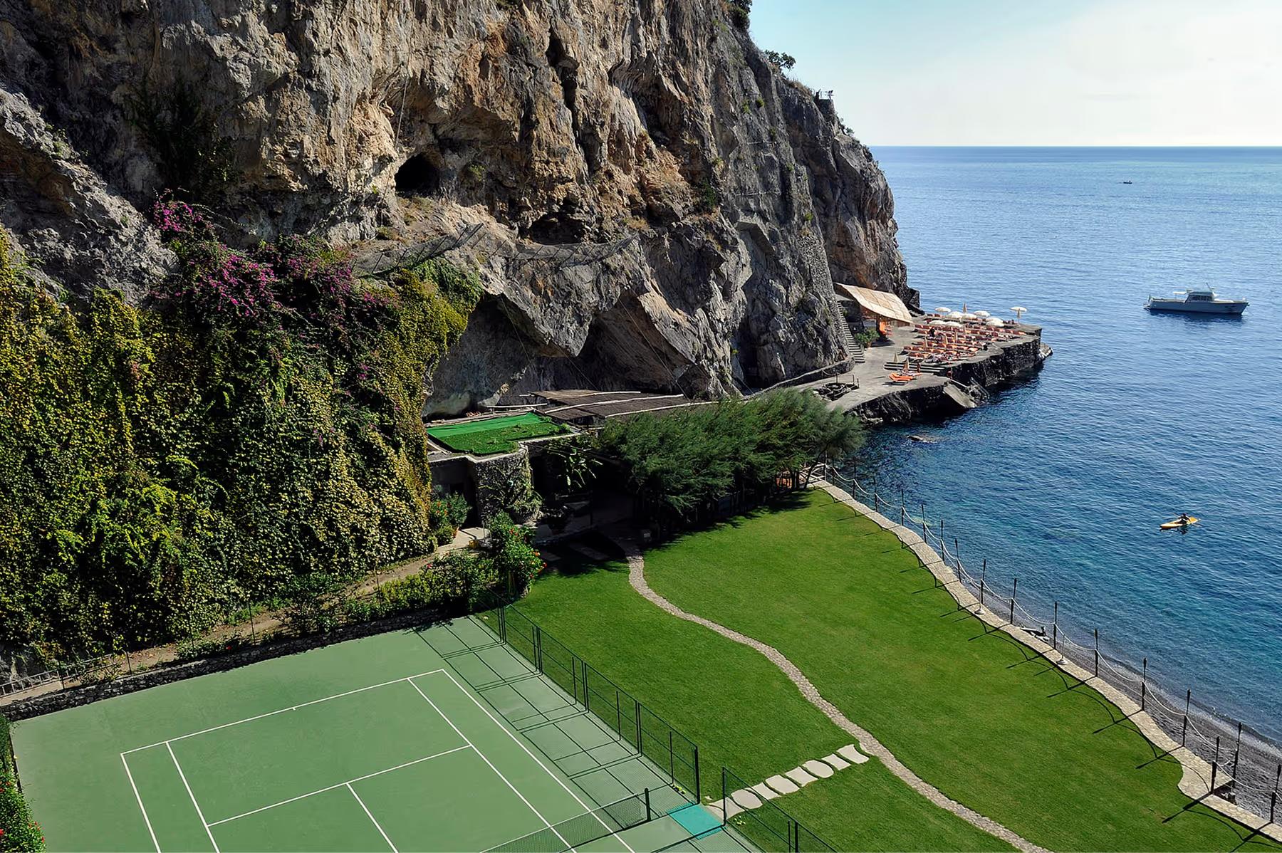 Il San Pietro di Positano: cliffside tennis facility with views of boats, sea, and surrounding dramatic coastline