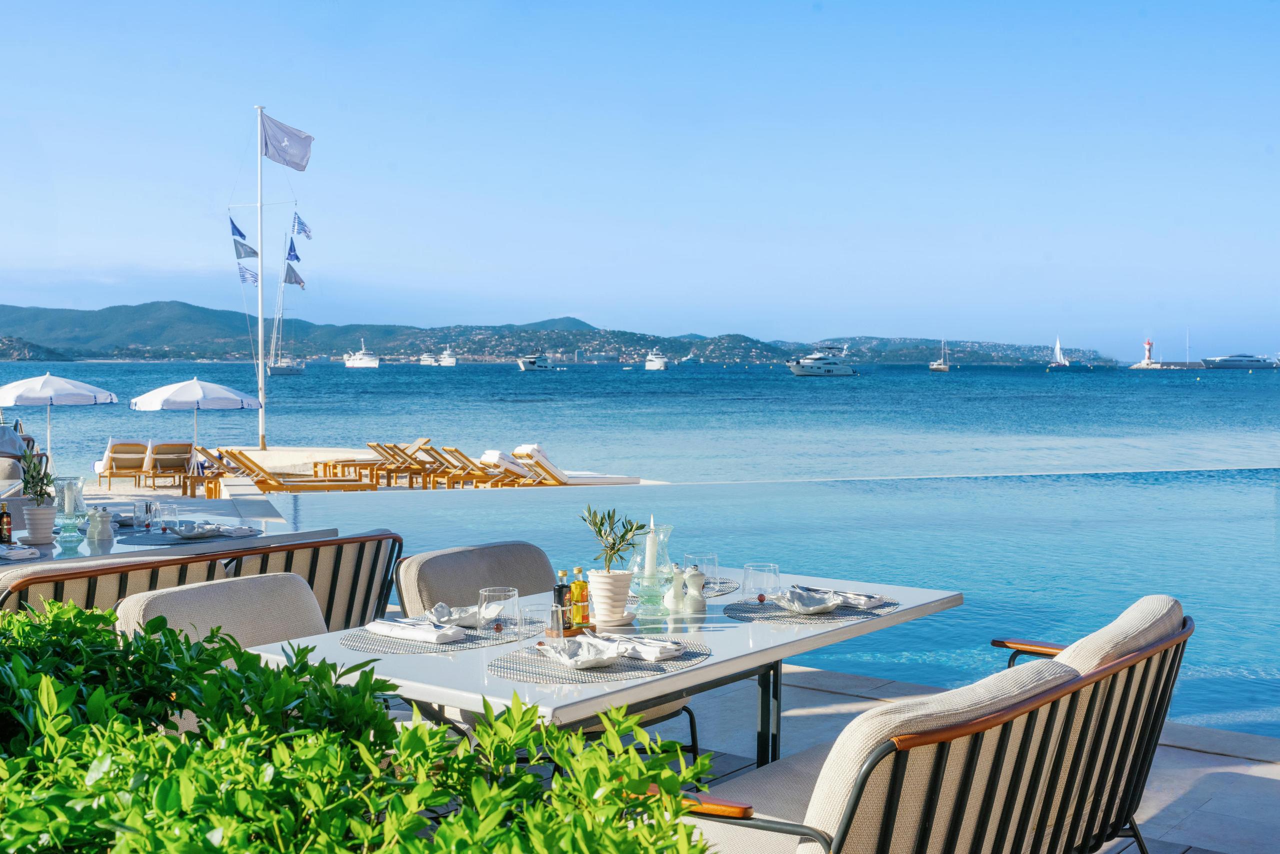 Outdoor dining table with sea views and anchored boats beyond