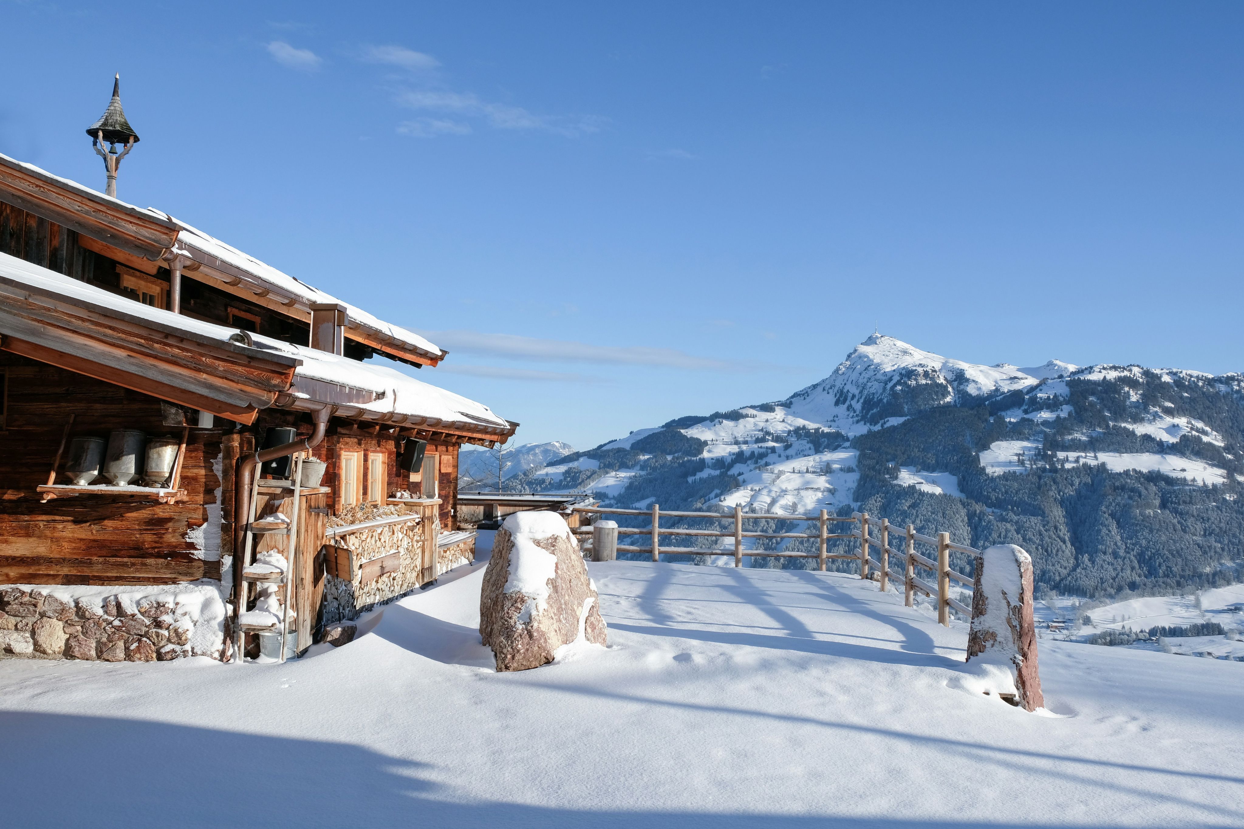 A snowy terrace and chalet in Kitzbühel with a peak in the distance